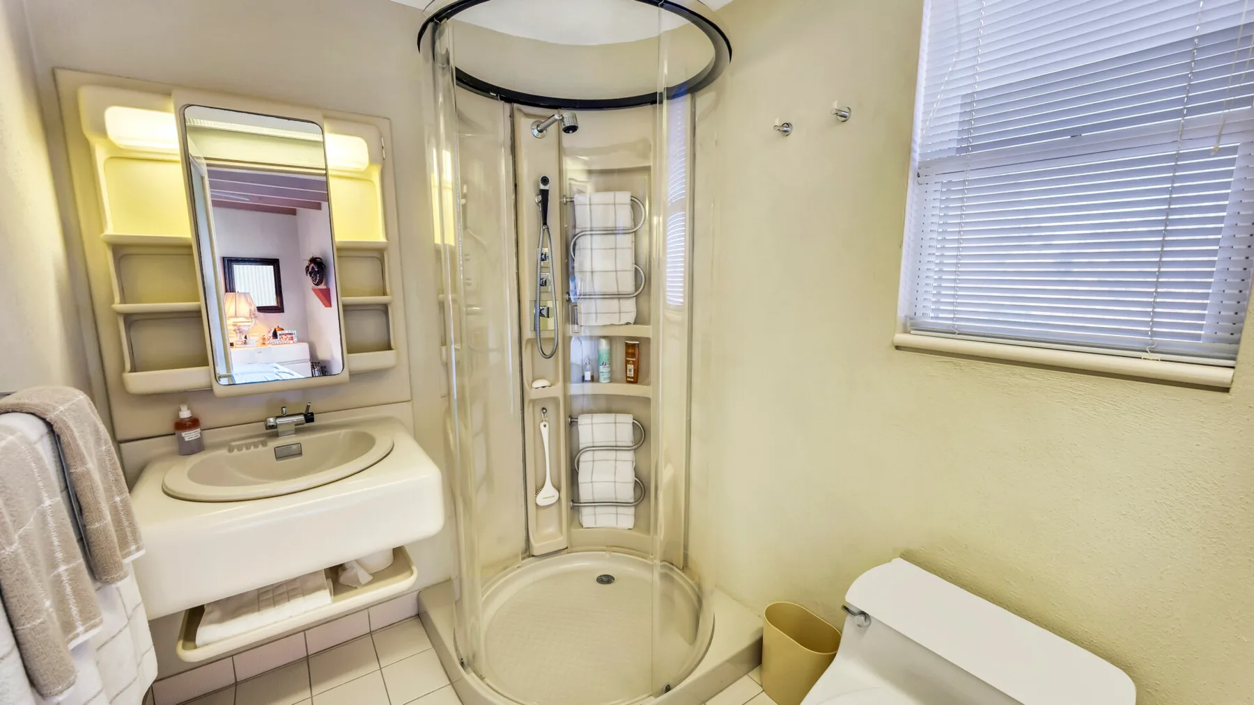A bathroom with a curved glass shower and a sink beneath a mirror.