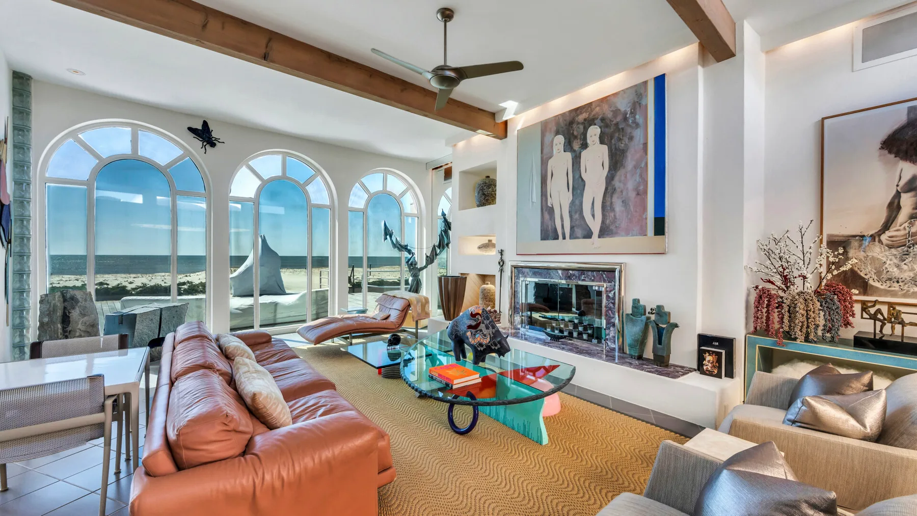 A bright living room with large arched windows and seating around a glass coffee table.