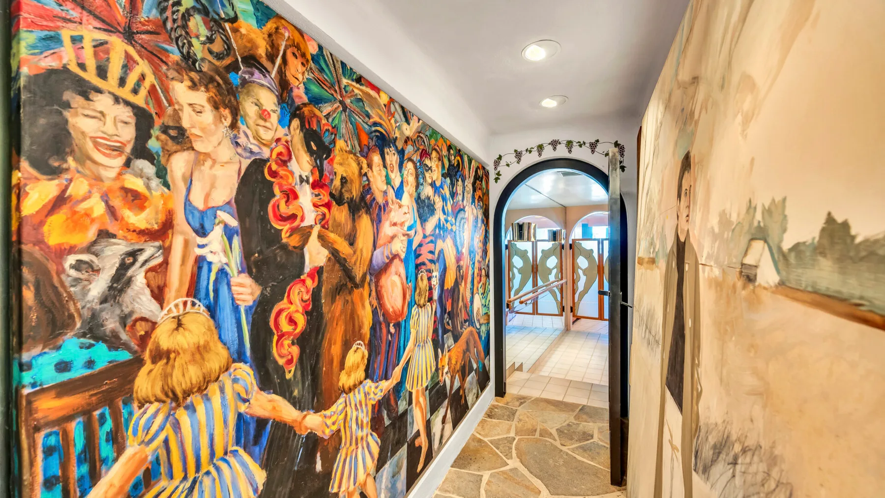 A narrow hallway features a colorful mural along one wall and an arched doorway.