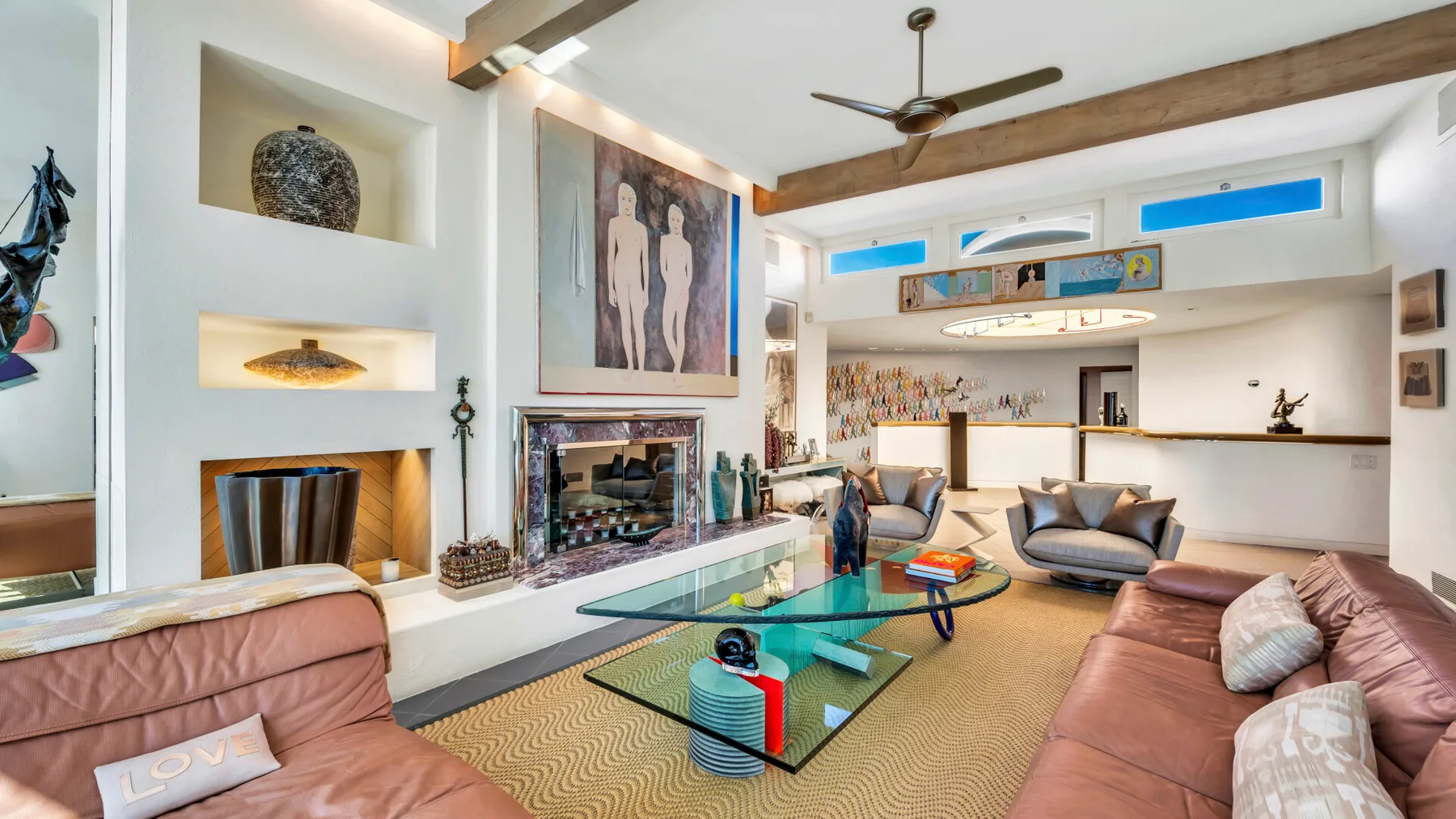 A bright living room with leather seating, a glass coffee table, and a fireplace.