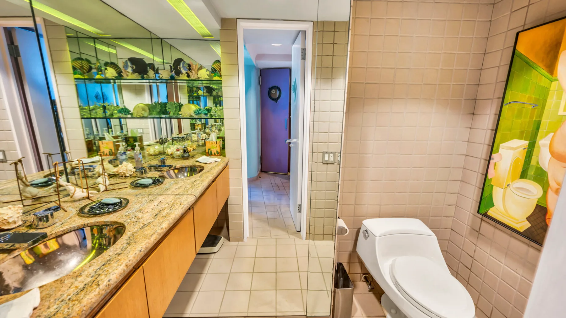 A tiled bathroom with a long vanity, sink, and toilet.