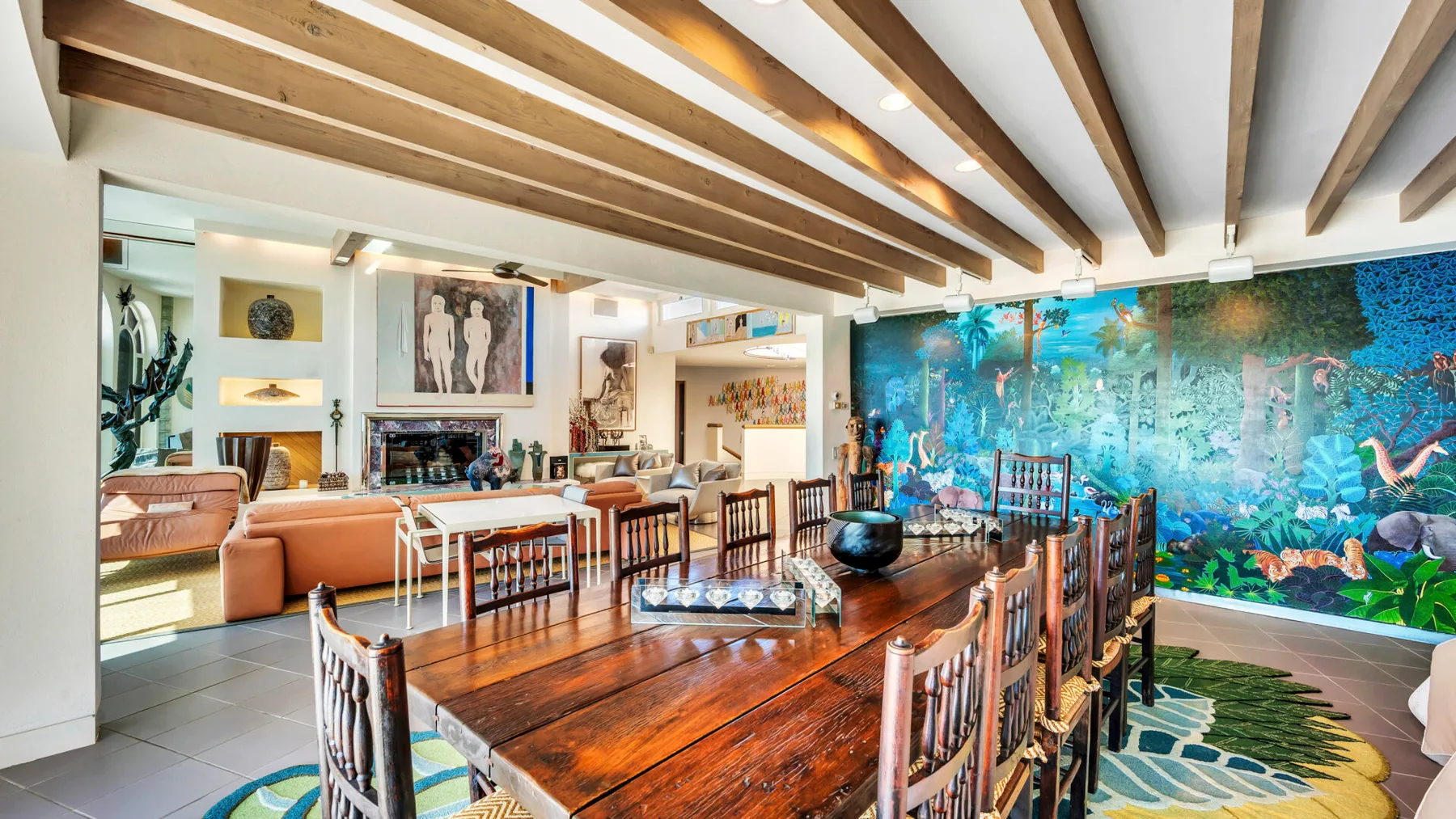 A dining area with a long wooden table and colorful mural.