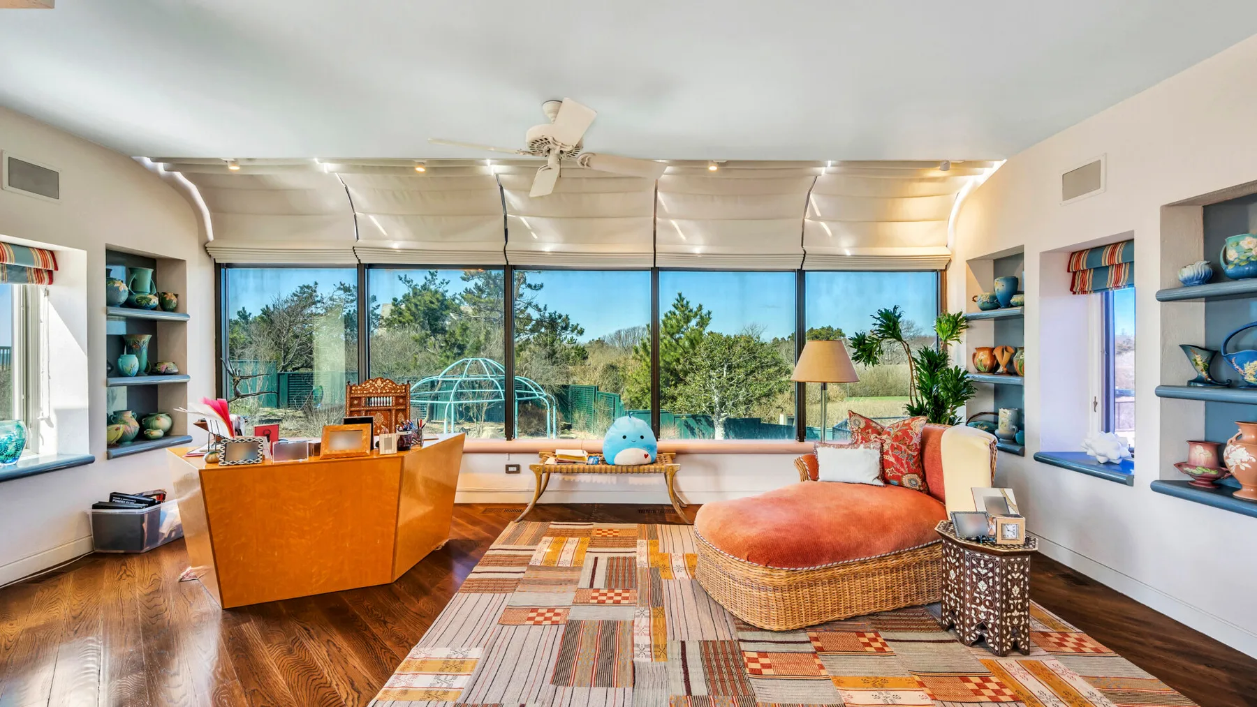 A bright living room with seating, a patterned rug, and large windows.