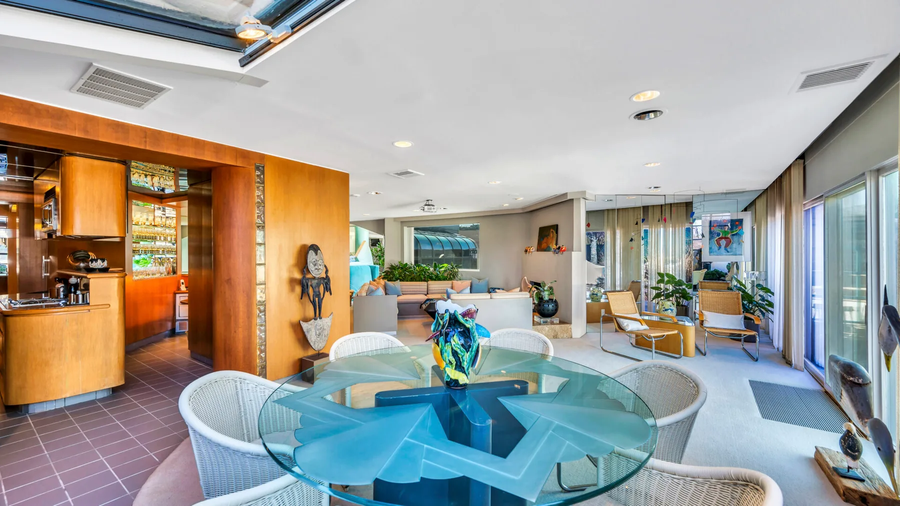 A bright living room with a round glass table and seating beside large windows.