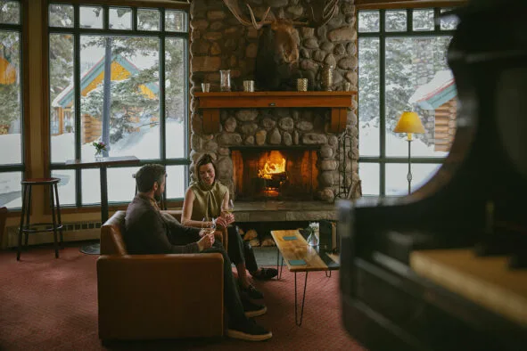 Guests sitting by a stone fireplace