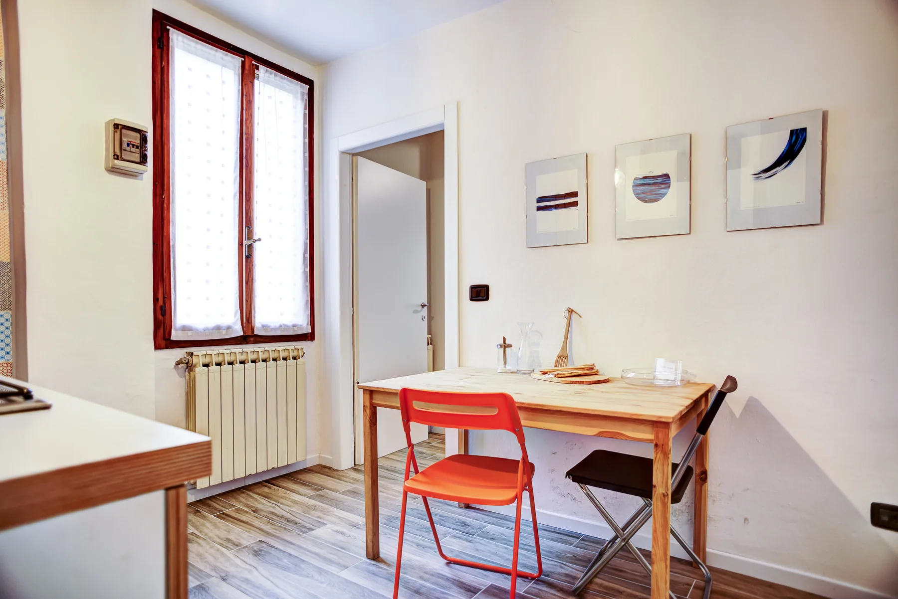A dining area with a wooden table, chairs, and framed artwork on the wall.