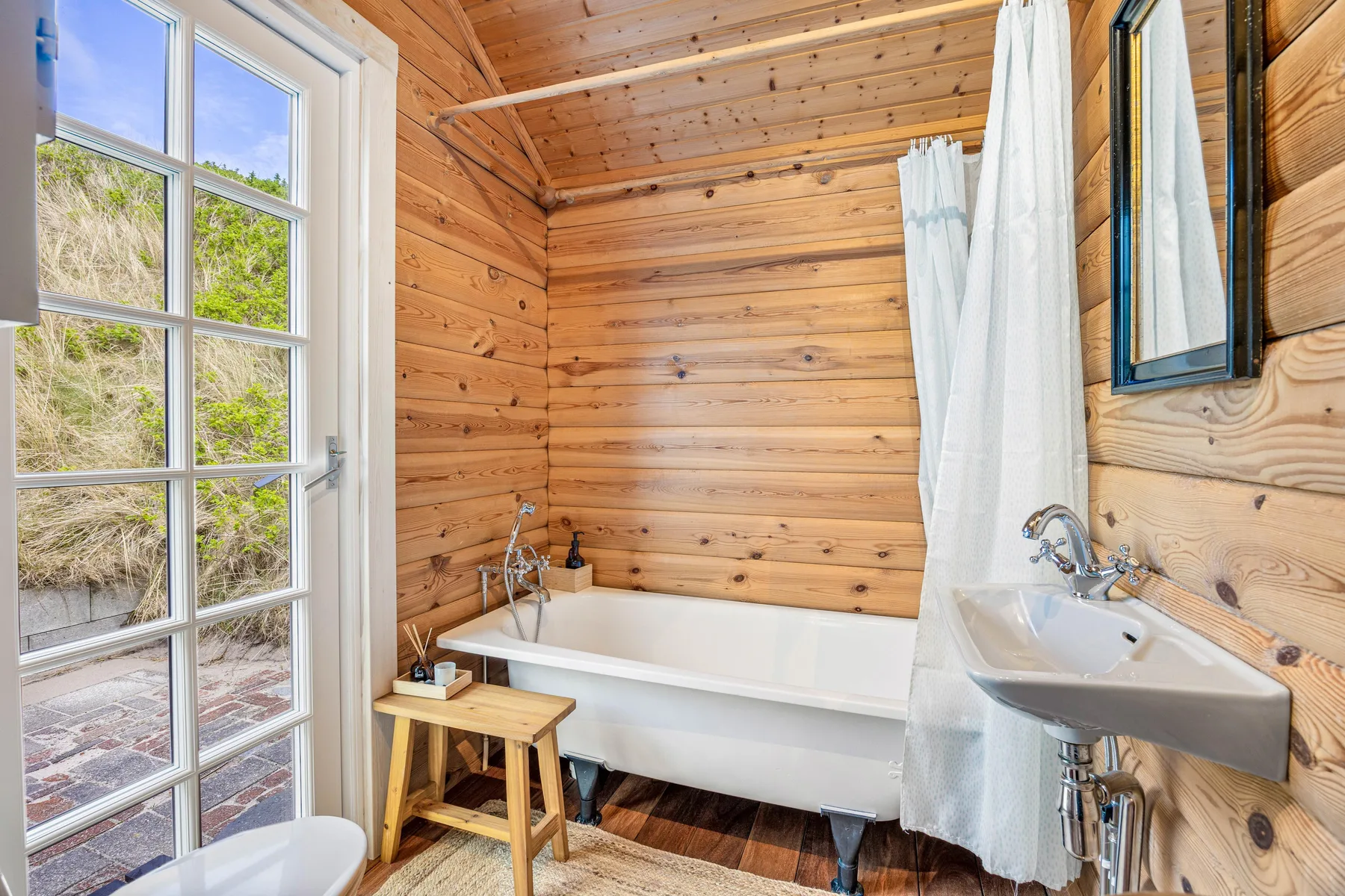 Un baño con bañera y lavabo junto a una puerta con paneles de vidrio.