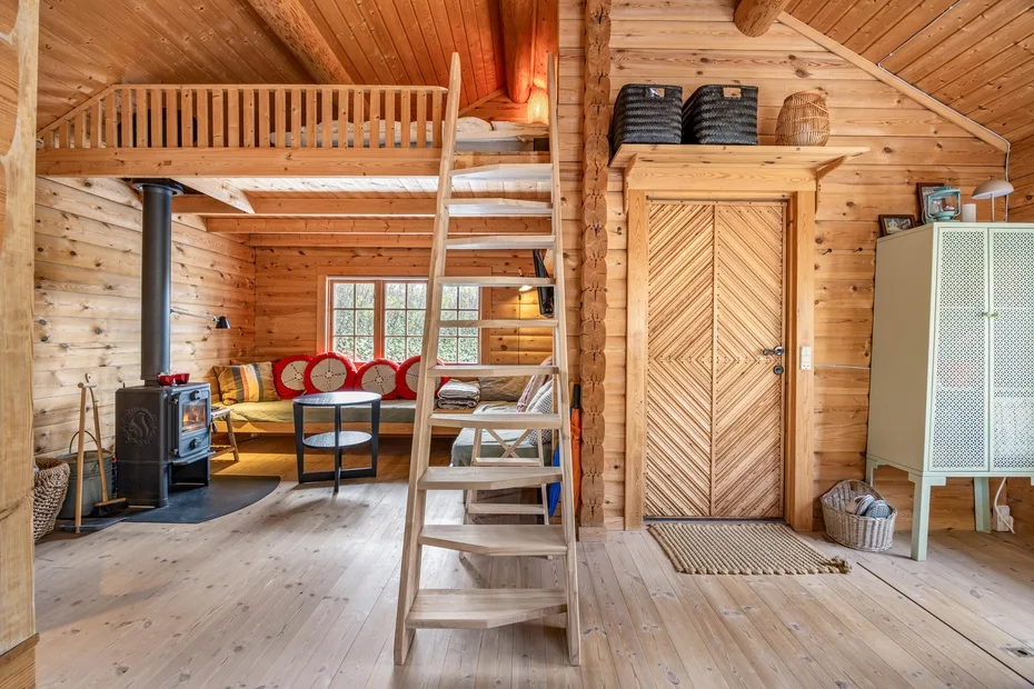 Una sala de estar de cabaña de madera con un altillo elevado y una estufa de leña.