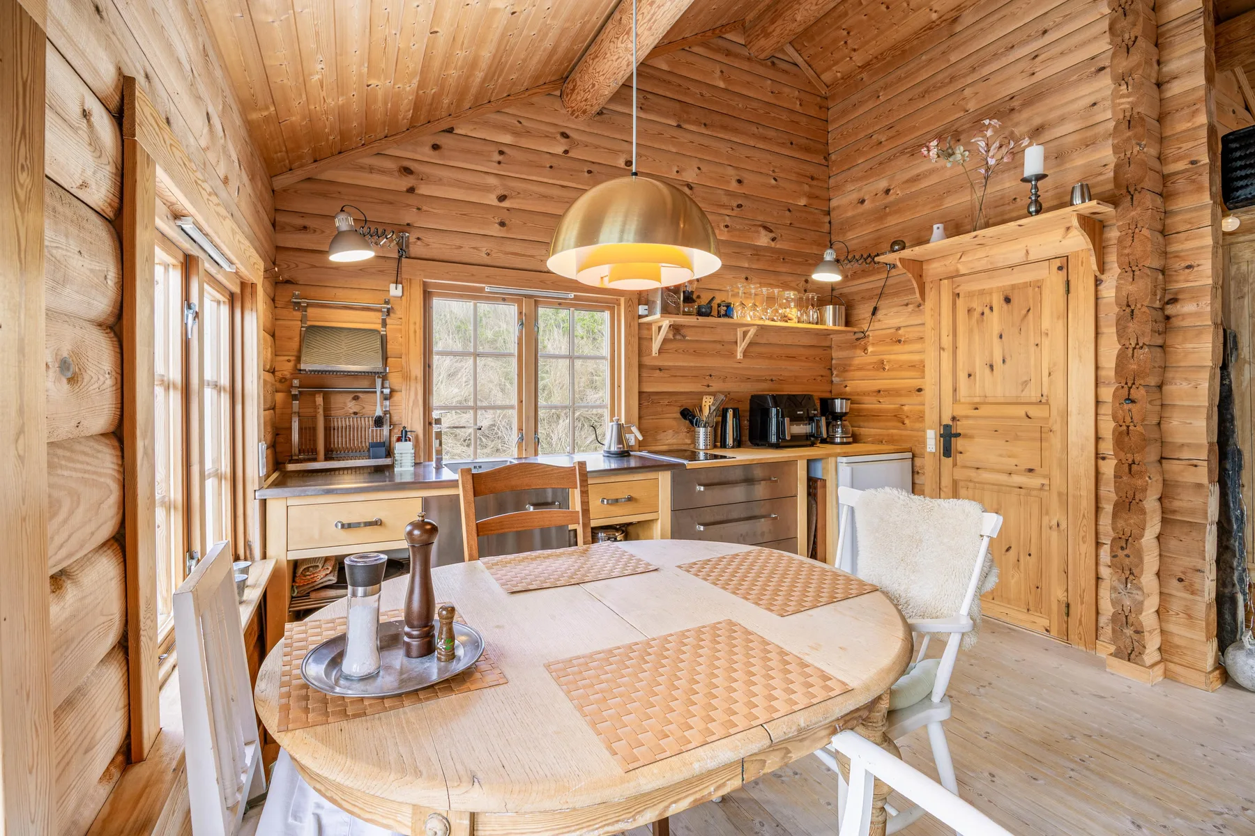 Una cocina y comedor revestidos de madera, con una mesa redonda en primer plano.