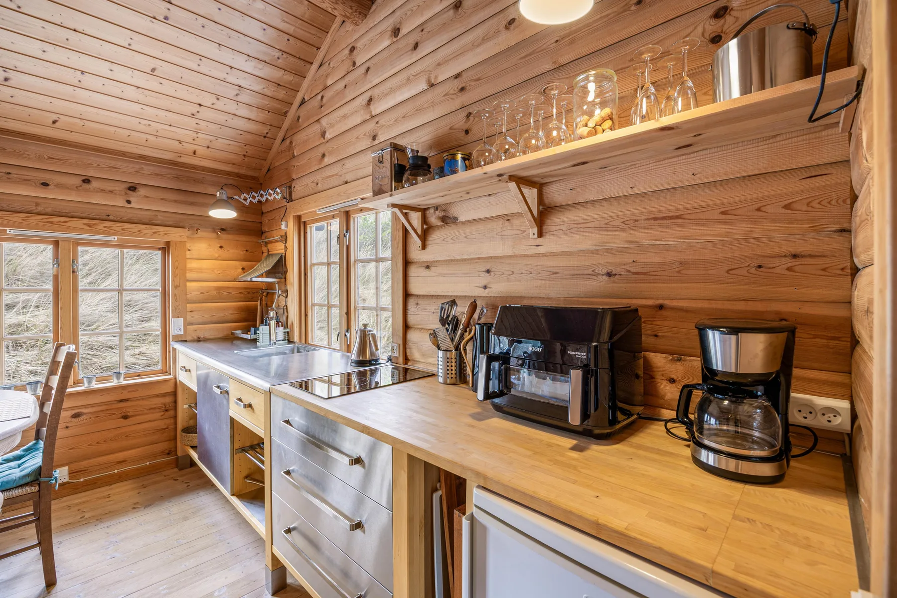 Una cocina revestida de madera con una encimera larga, fregadero y pequeños electrodomésticos.