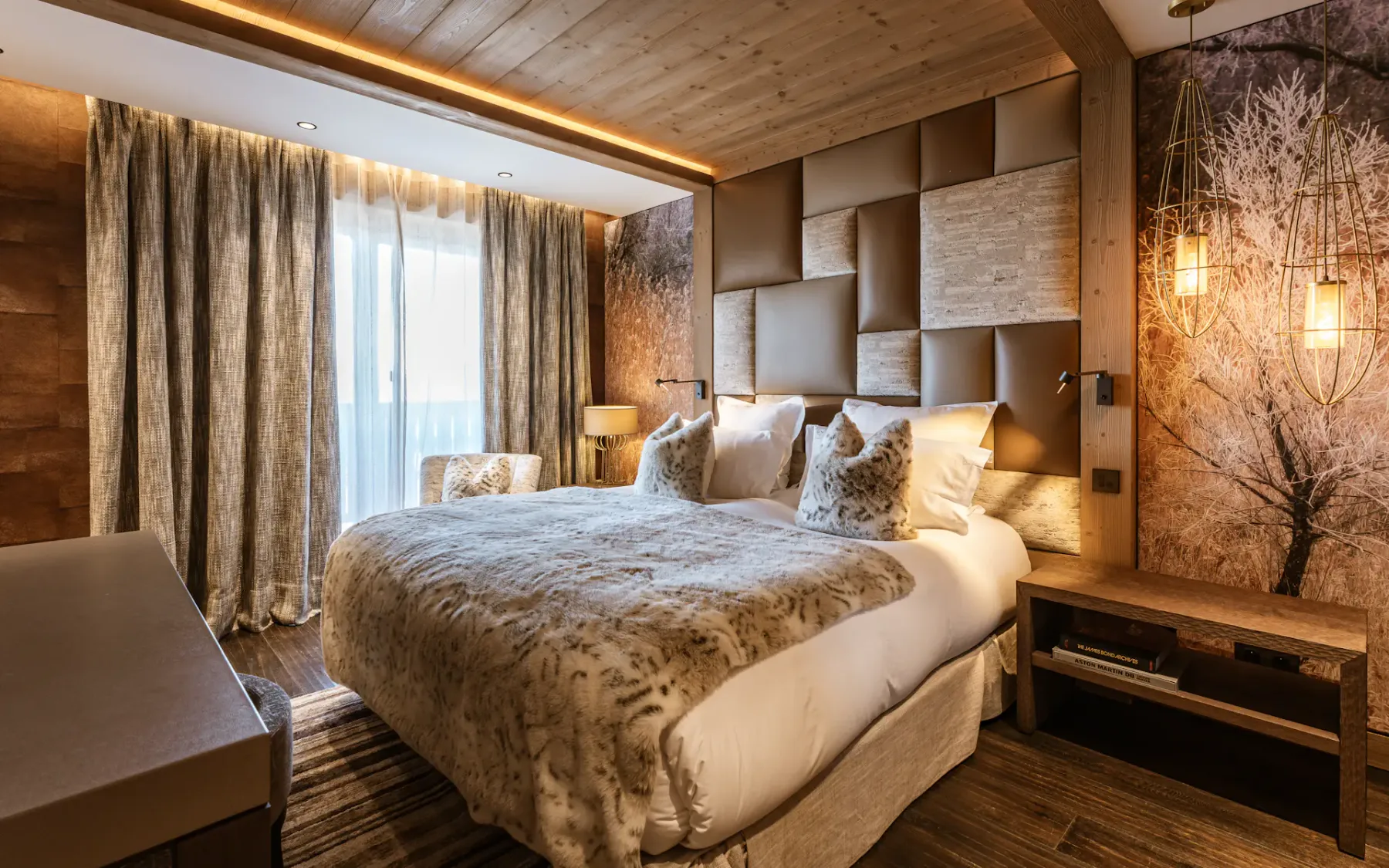 Cozy bedroom with a large bed, wooden accents, warm lighting, and a nature-themed wall mural. Draped curtains cover a window.