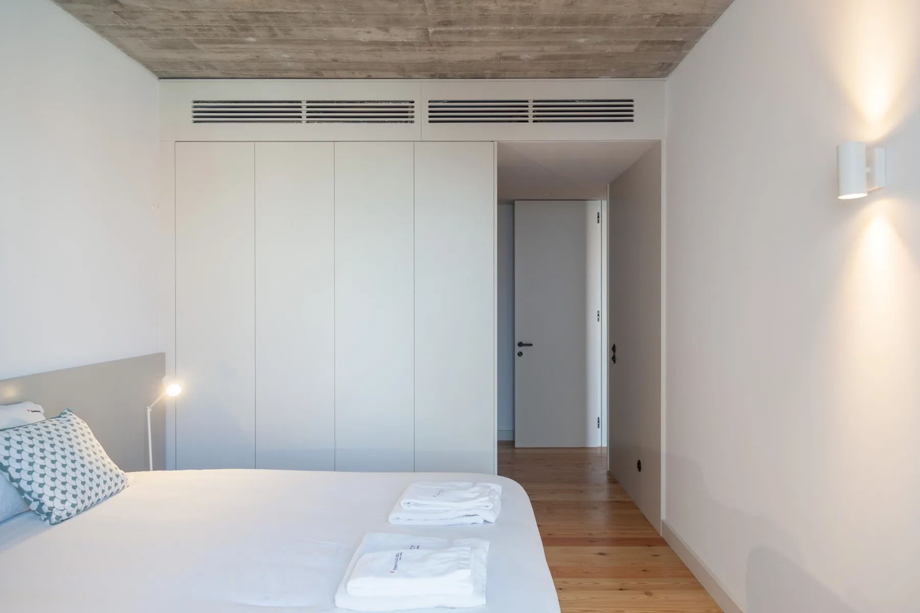 A bedroom with a bed, built-in wardrobes, and a doorway.