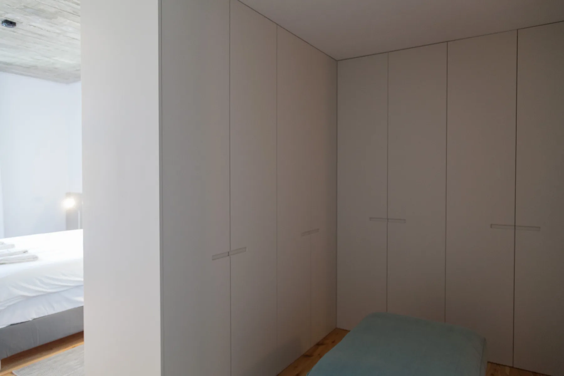 A bedroom with built-in wardrobes and part of a bed visible.
