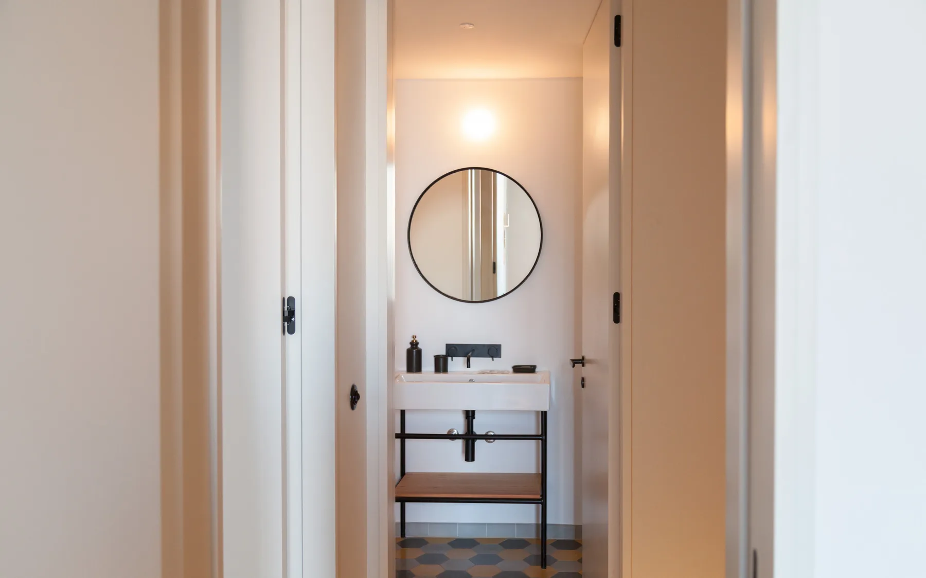 A bathroom vanity with a round mirror is visible through an open doorway.