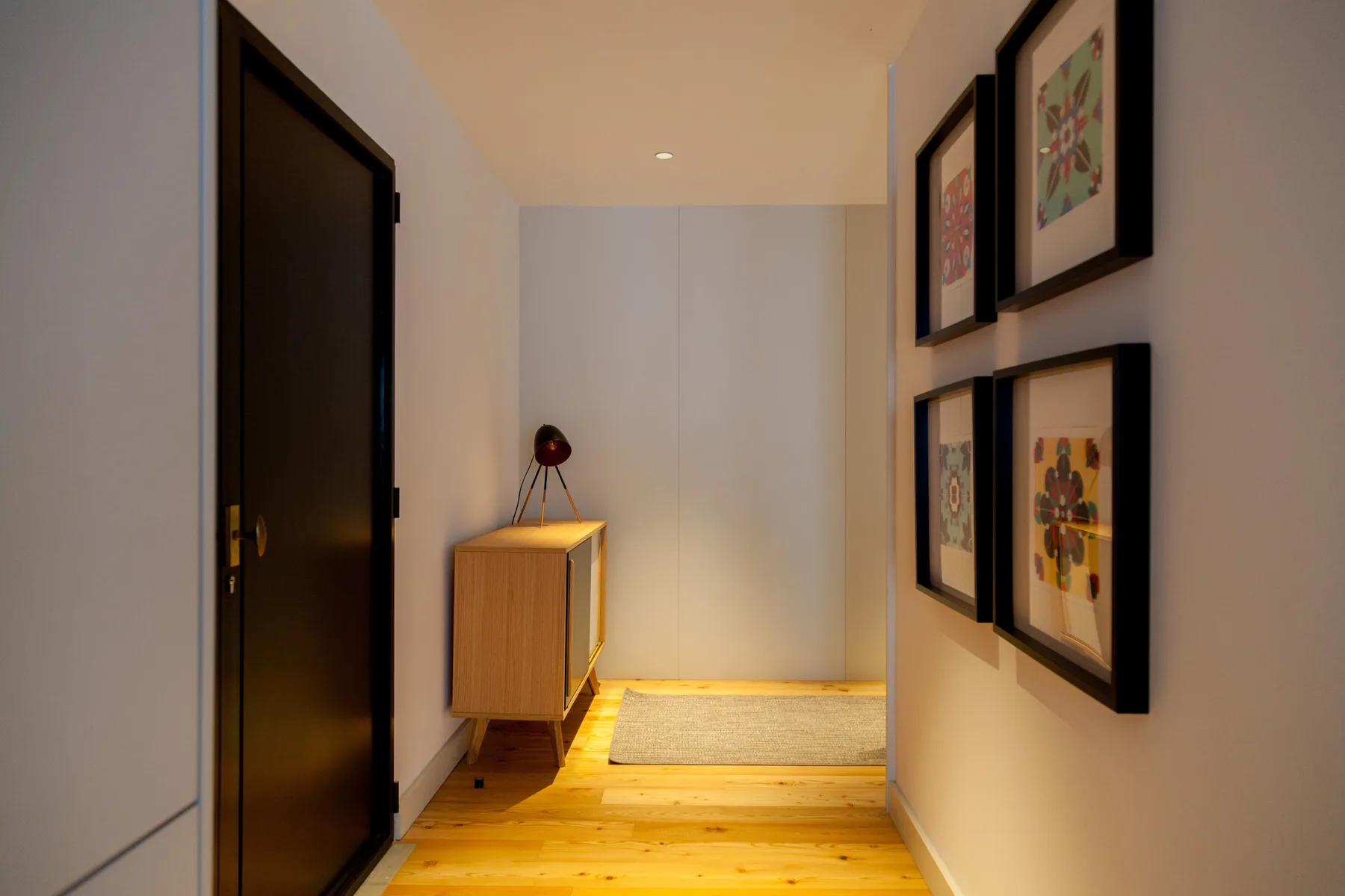 A hallway with a wooden cabinet and framed artwork on the wall.