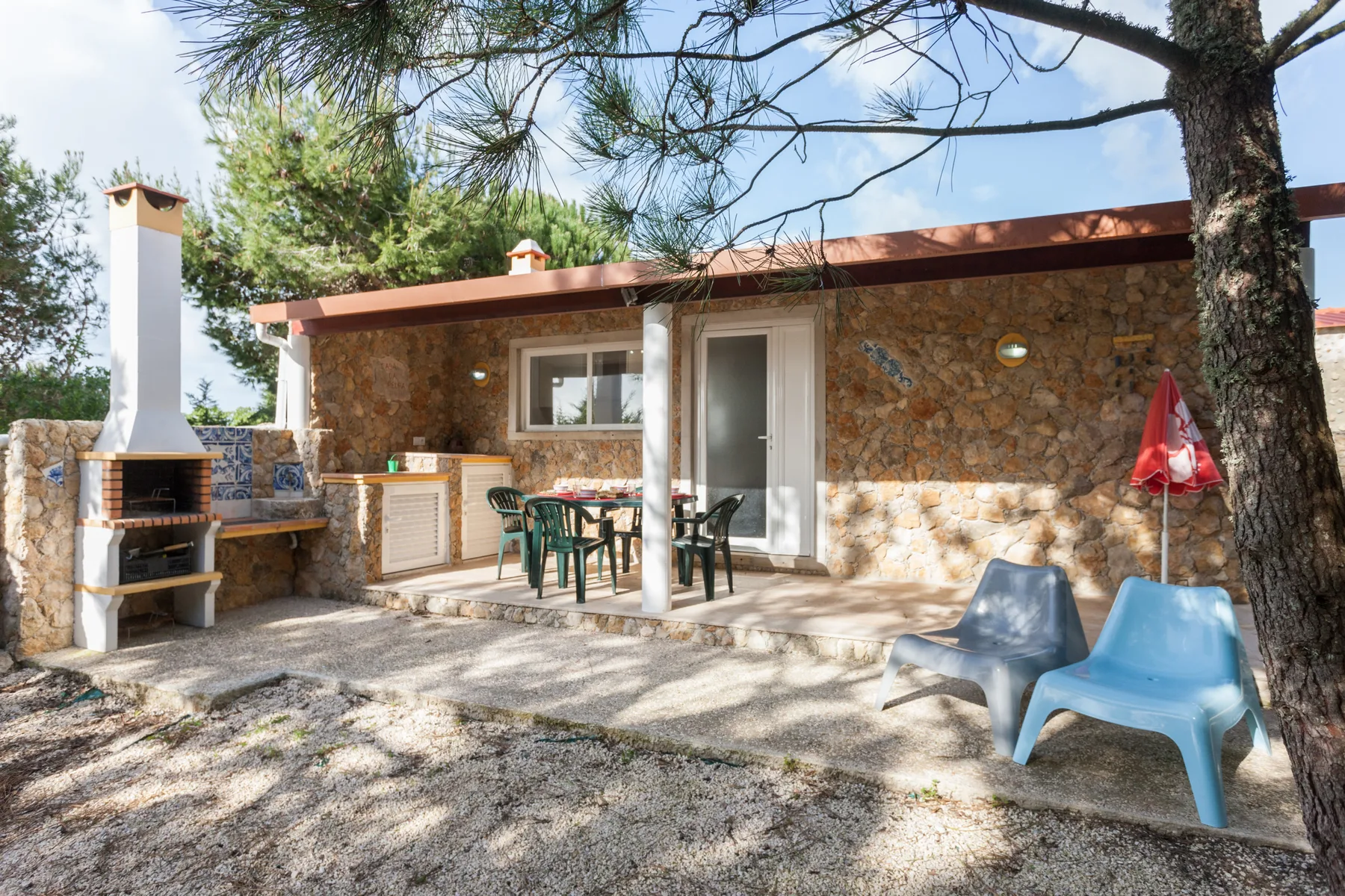 A stone patio with outdoor seating and a built-in barbecue beside the house.