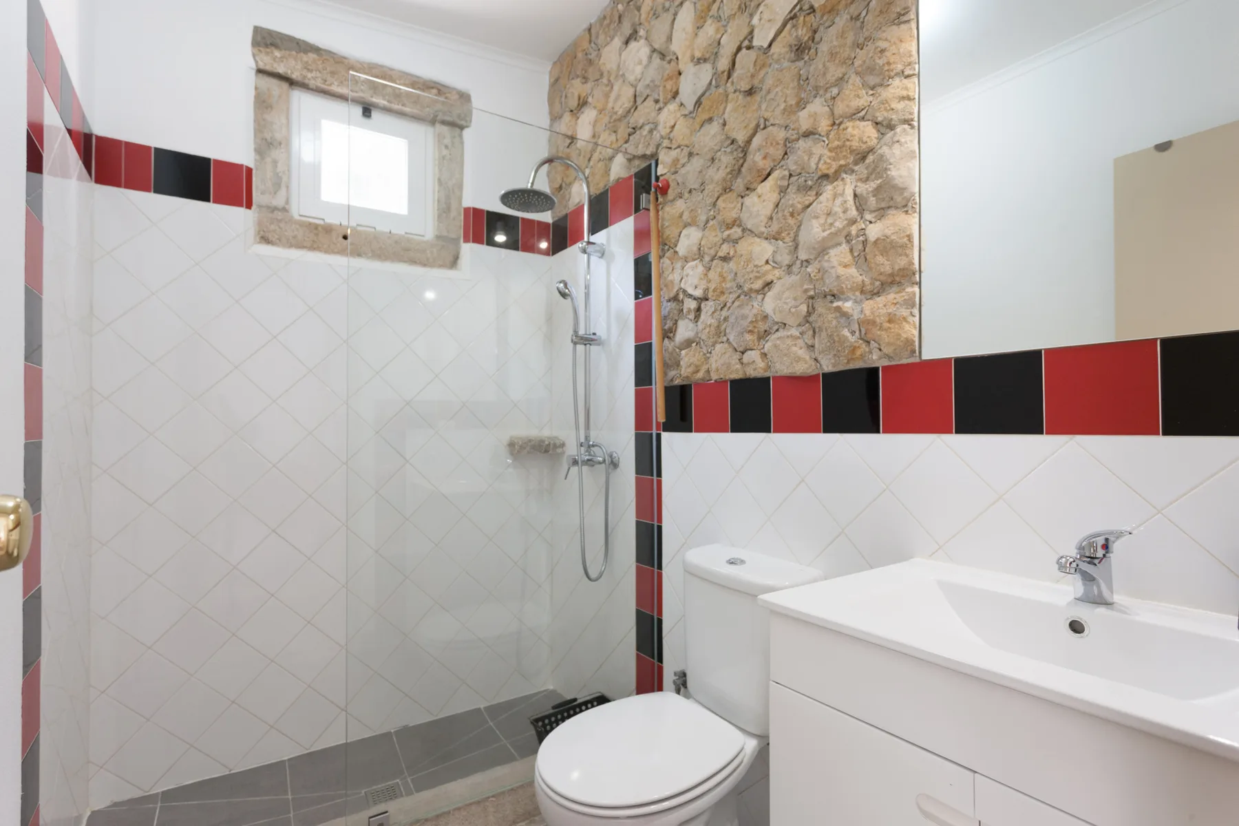 A tiled bathroom with a shower, toilet, and sink.