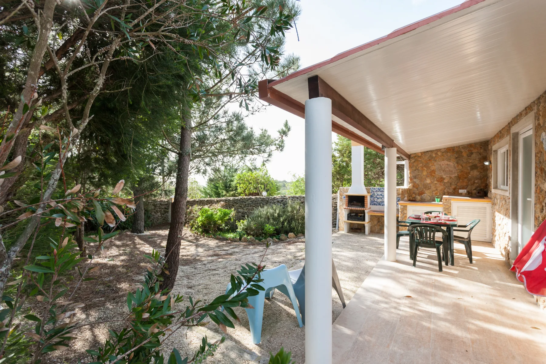 A covered outdoor patio with a dining table beside a garden.