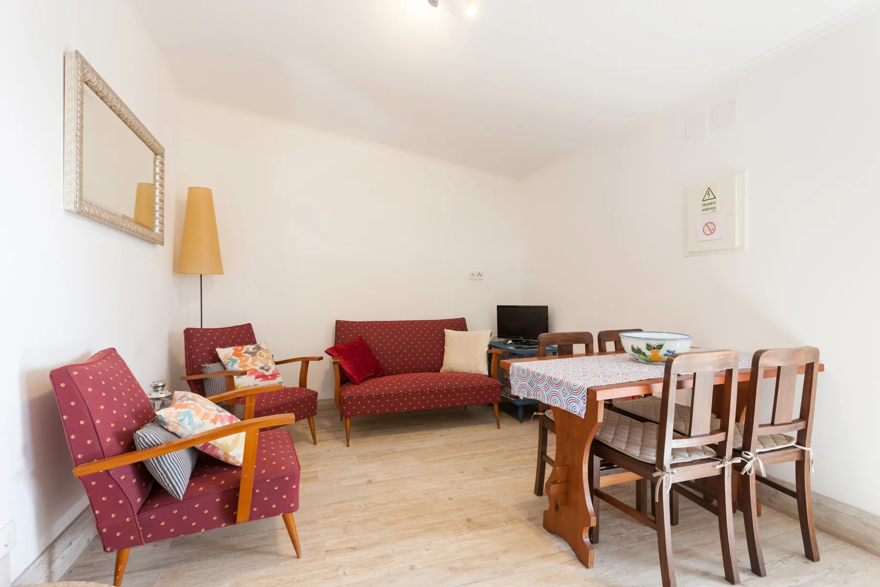 A living and dining area with red seating, a television, and a wooden table.