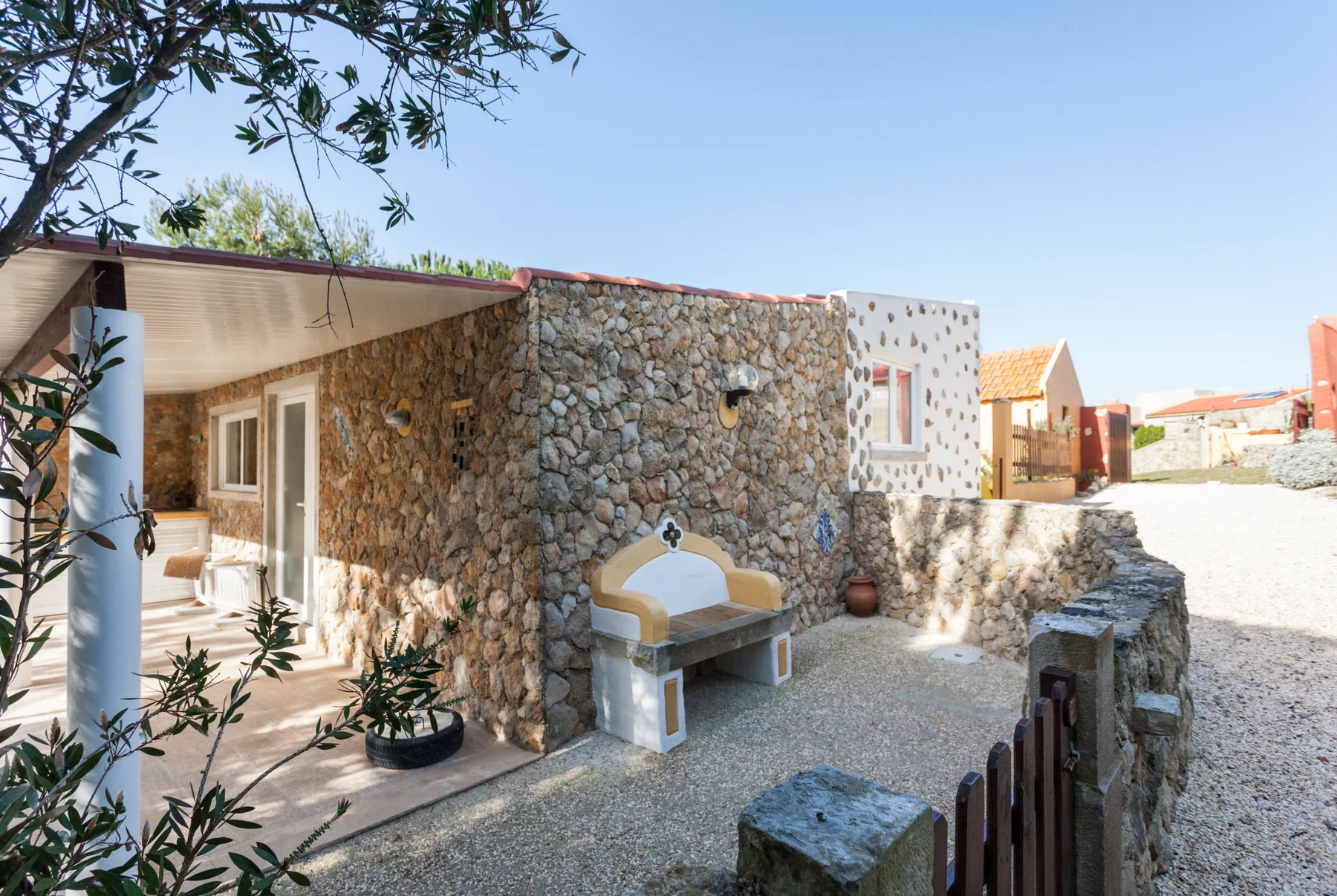 A stone courtyard with a built-in outdoor bench beside a covered patio.