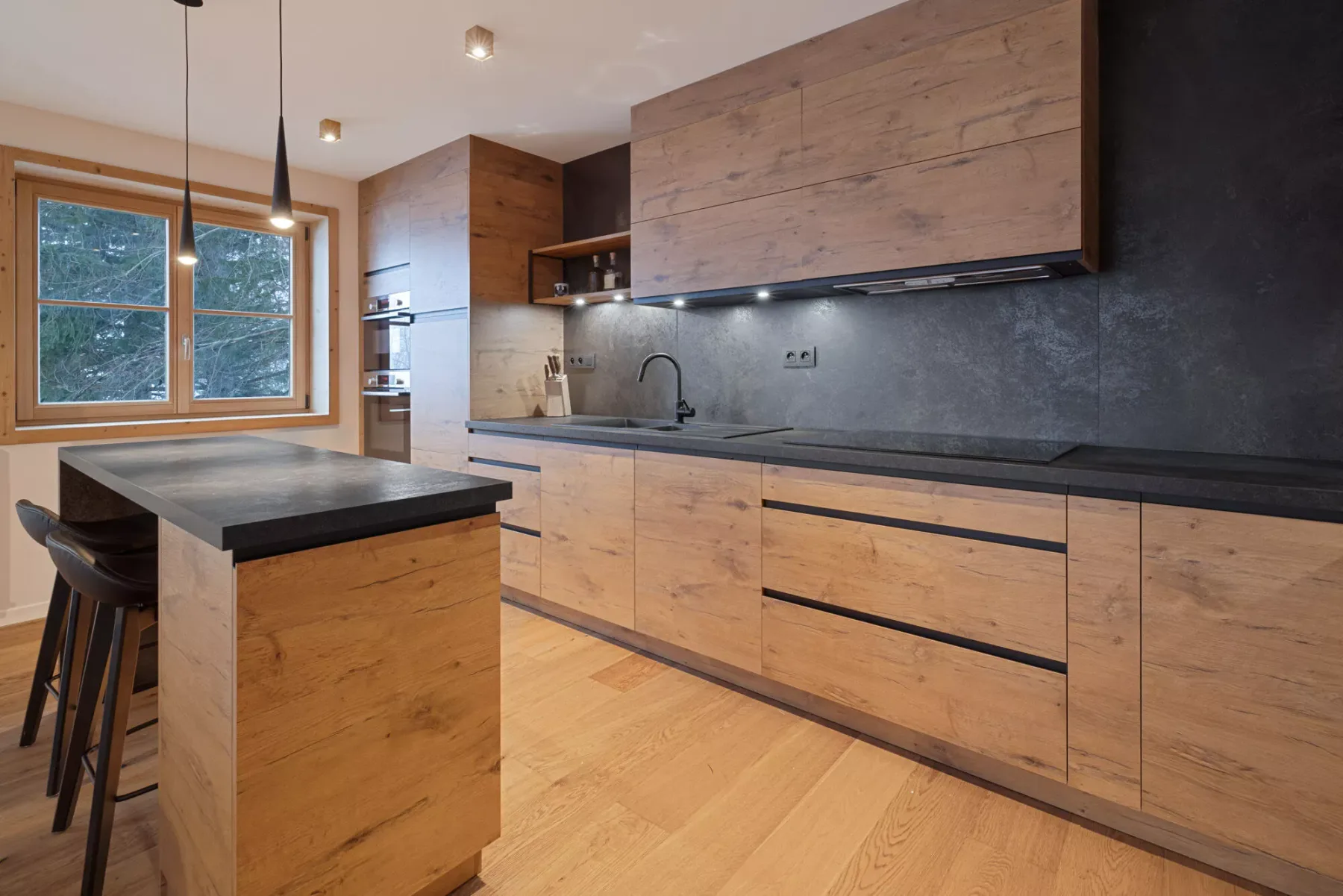 A modern kitchen with wood cabinetry, a central island, and a window.