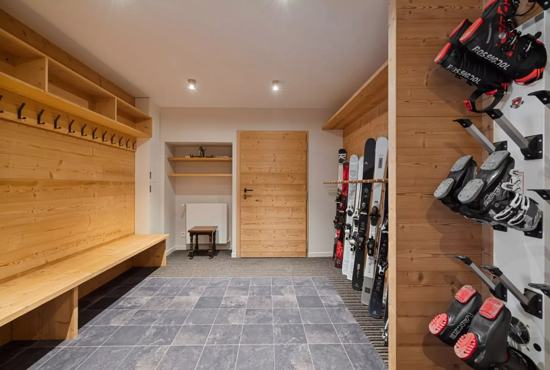 Un cuarto de almacenamiento de esquís revestido de madera, con un banco y soportes para equipo.