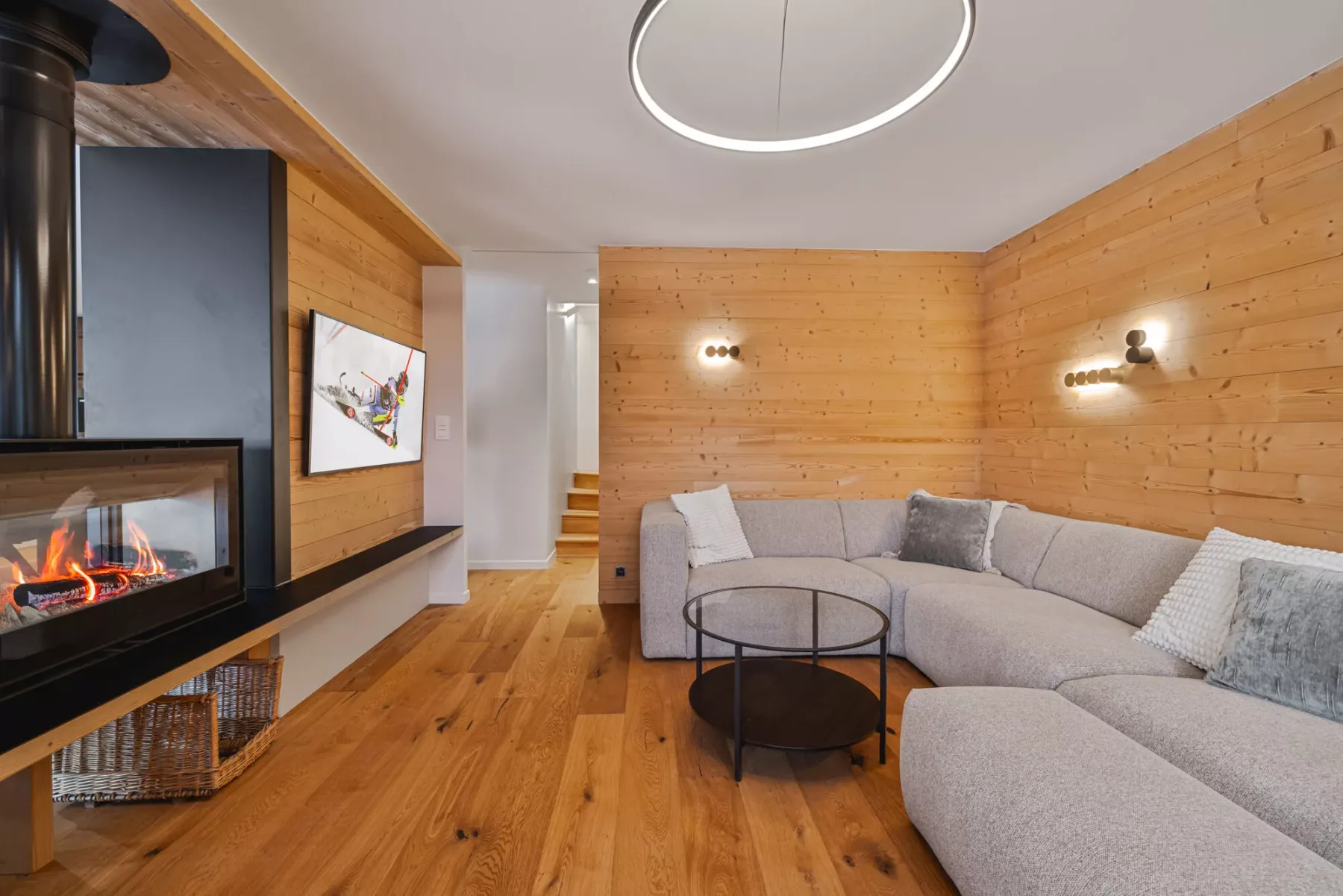 A wood-paneled living room with a sectional seating area and fireplace.