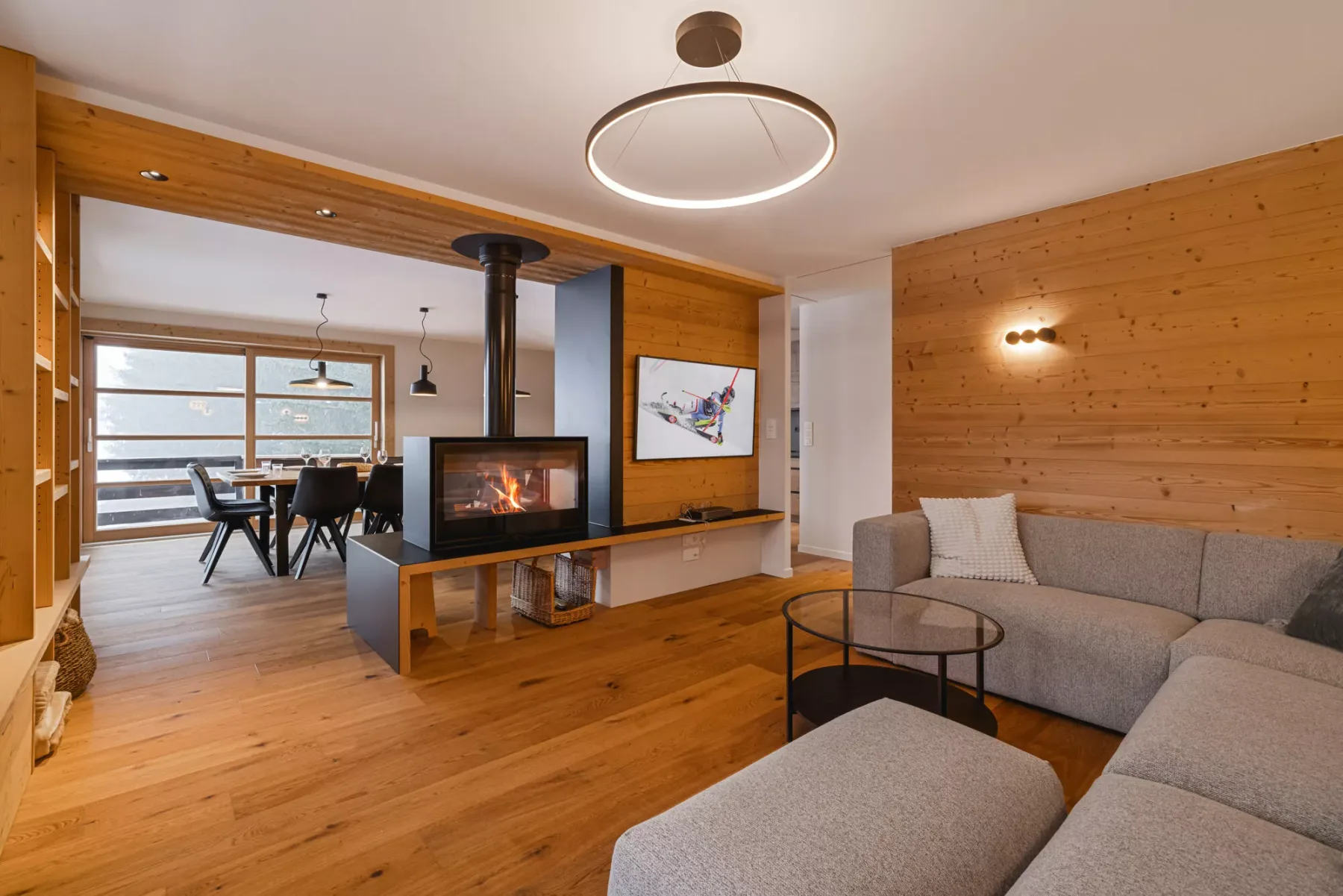 A wood-paneled living room with seating, a fireplace, and a dining area.