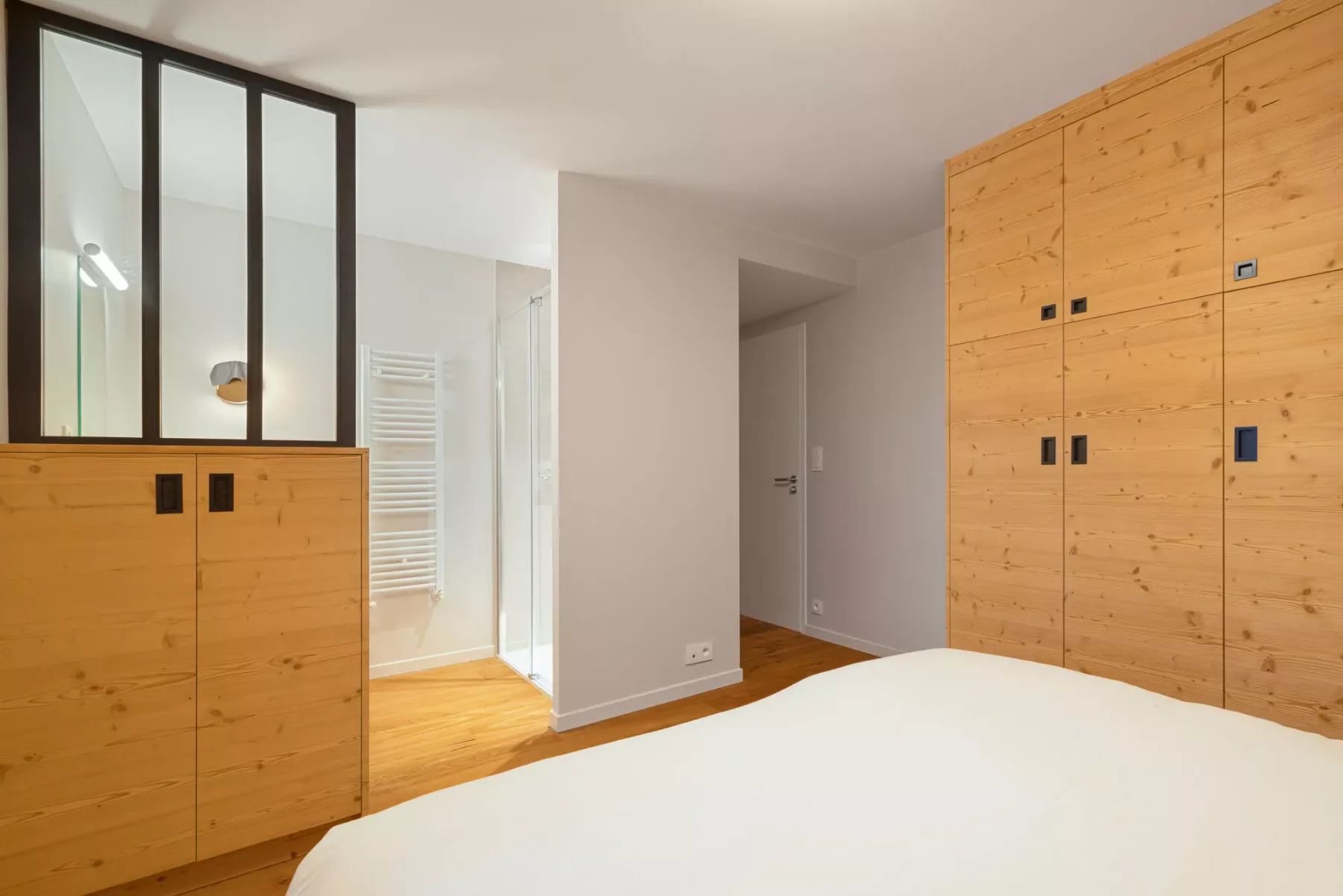 Dormitorio con una cama en primer plano y armarios de madera junto a la pared.