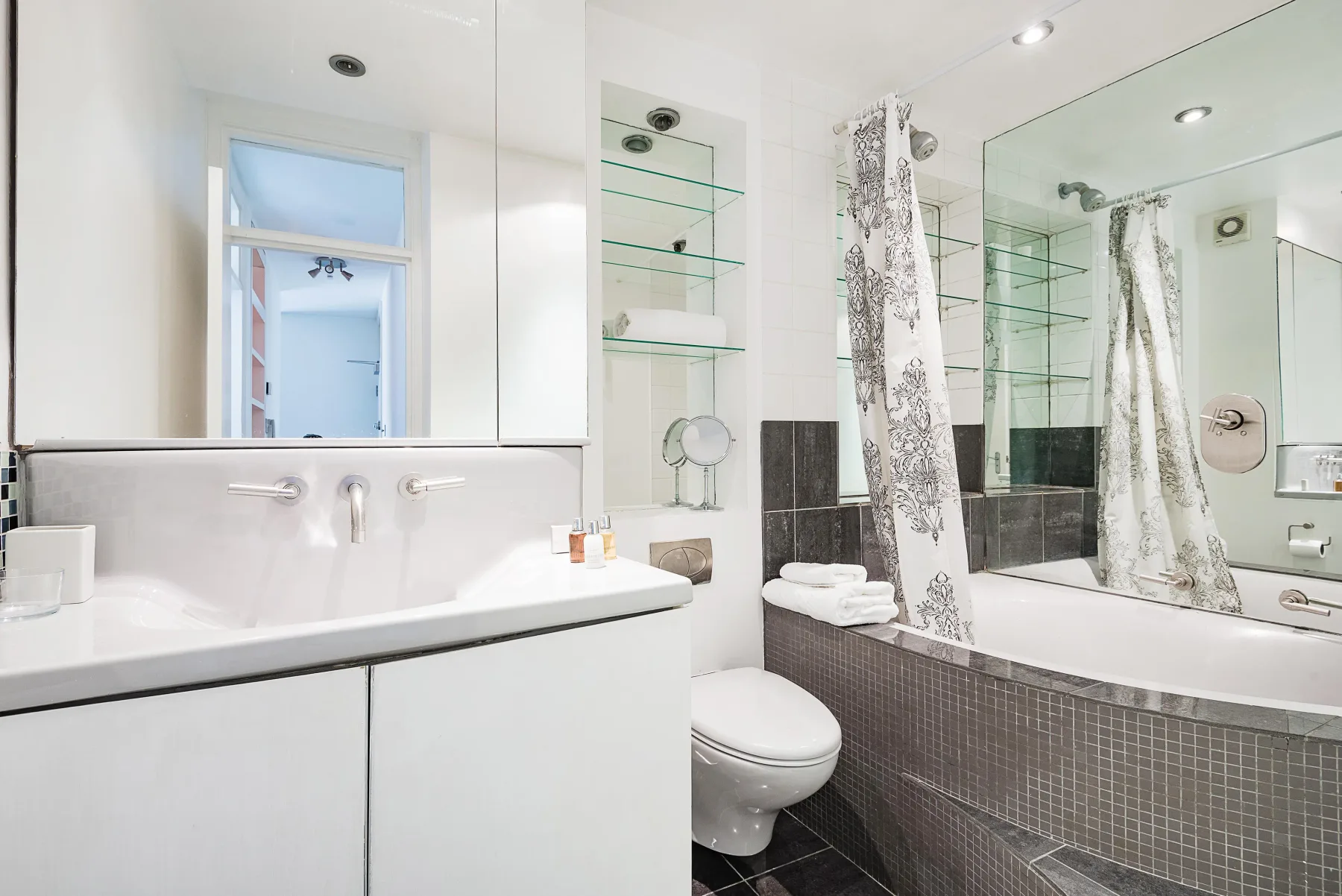 Un baño luminoso con lavabo, inodoro y bañera.
