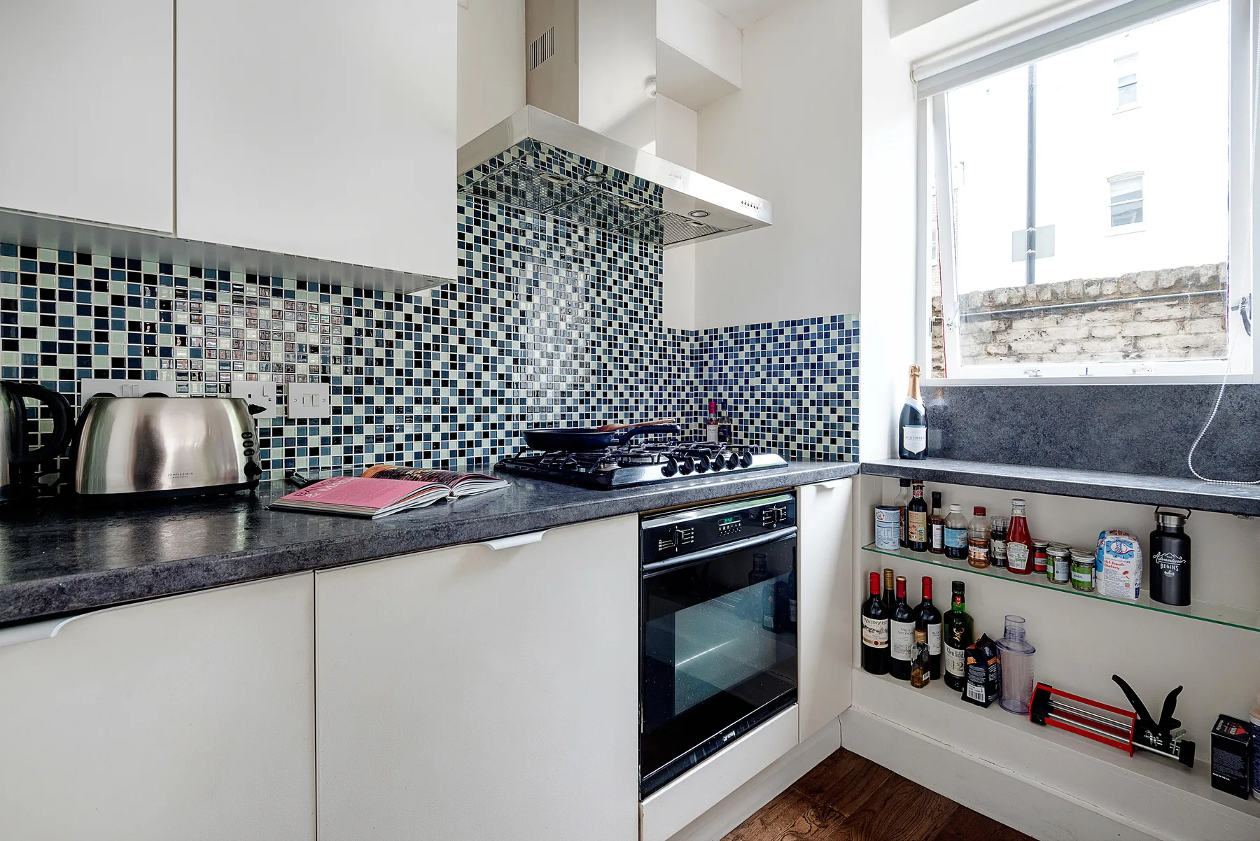 Una cocina luminosa con salpicadero de azulejos, encimera y una ventana grande.