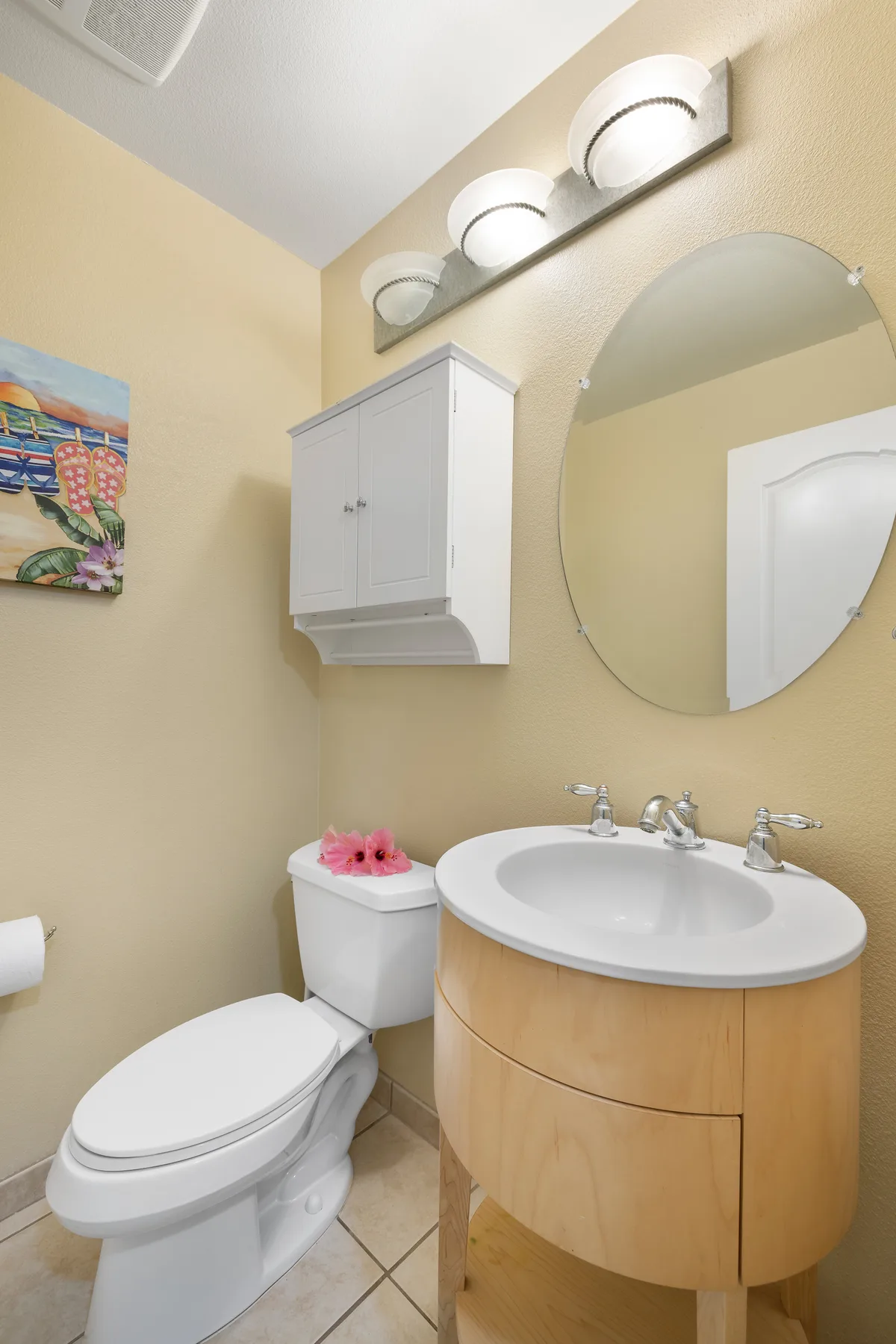A bathroom with a toilet, sink, and round wall mirror.