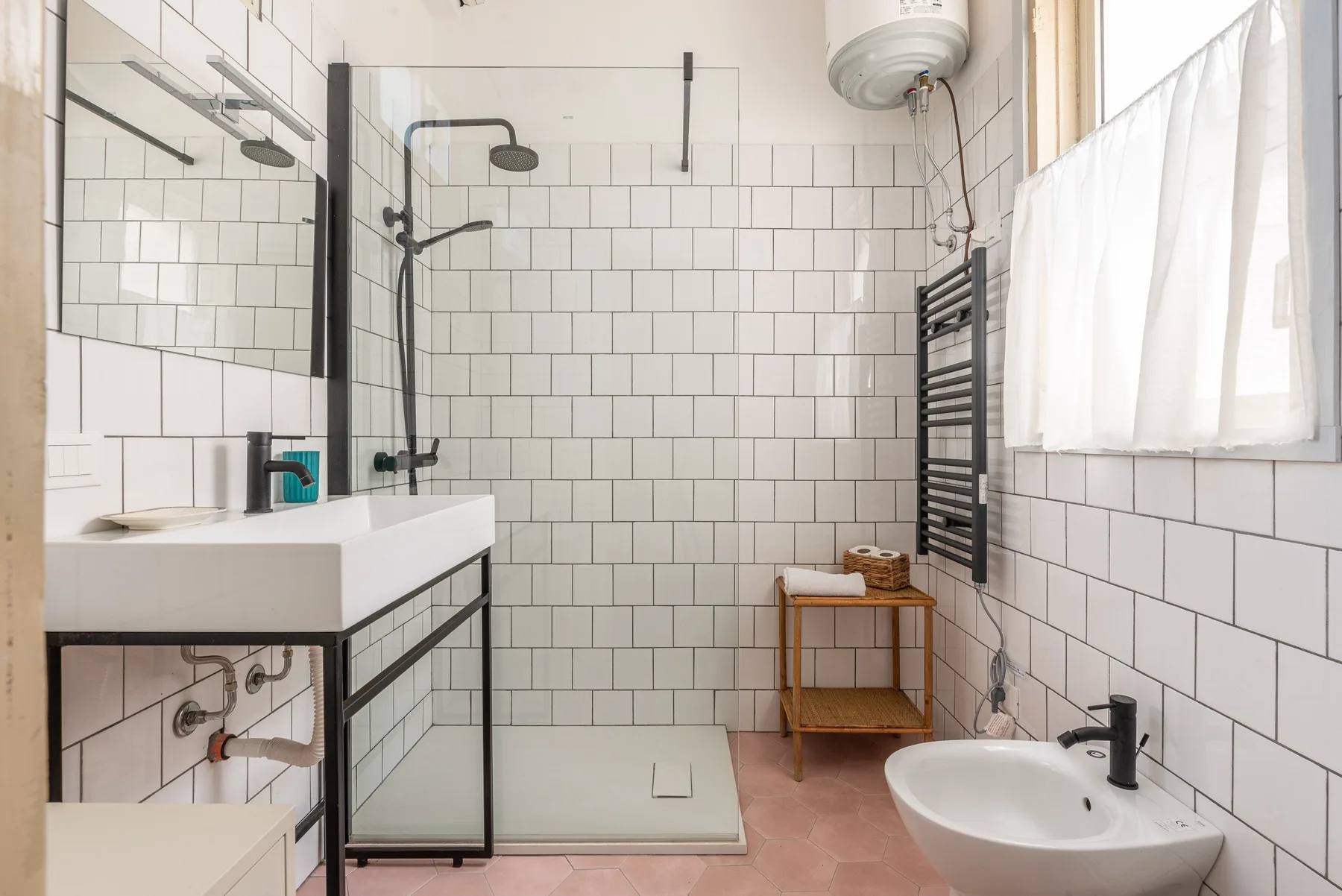 Un baño luminoso con ducha, lavabo y ventana.
