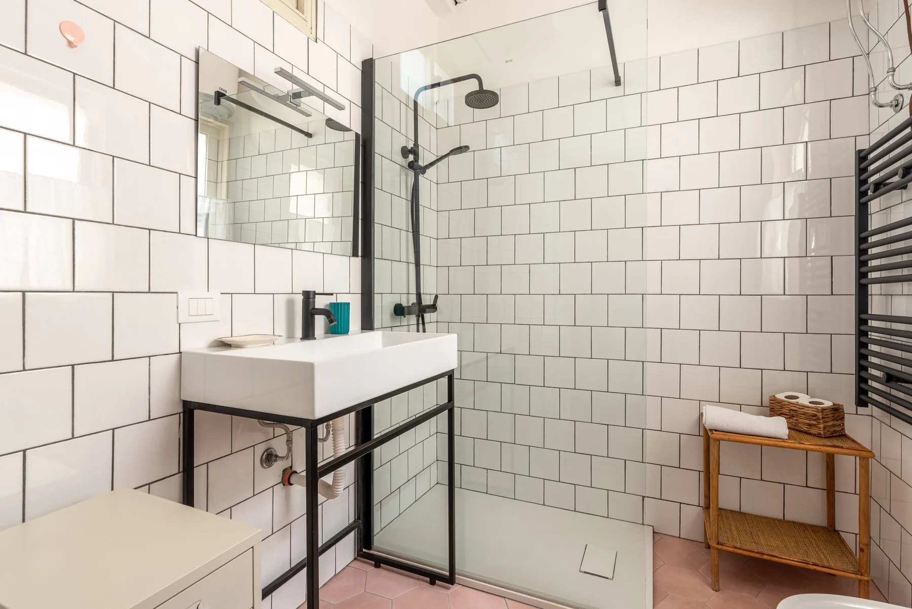 Un baño con azulejos, lavabo y ducha de cristal.