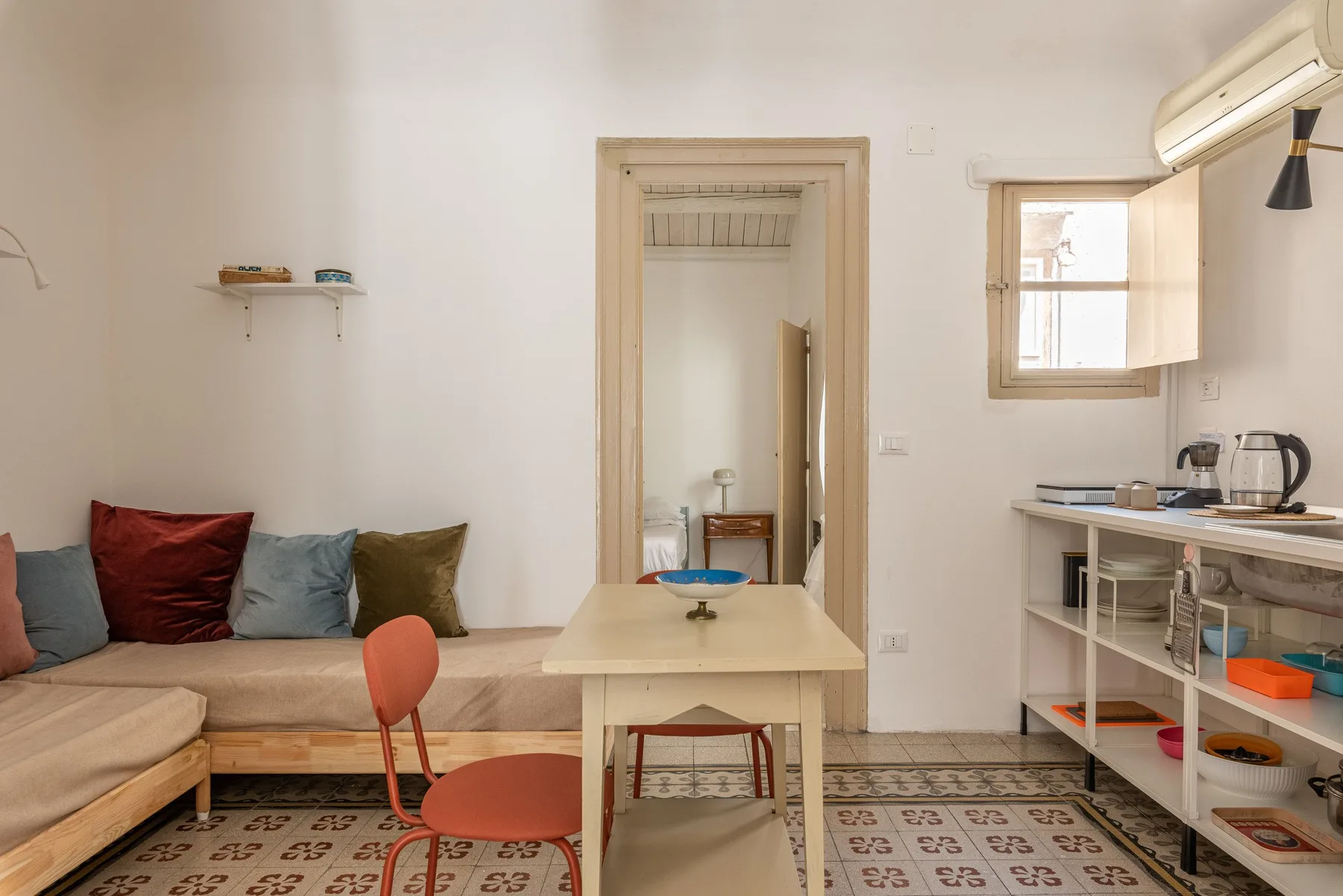Una habitación compacta con asientos, una mesa y una pequeña cocina junto a la pared.
