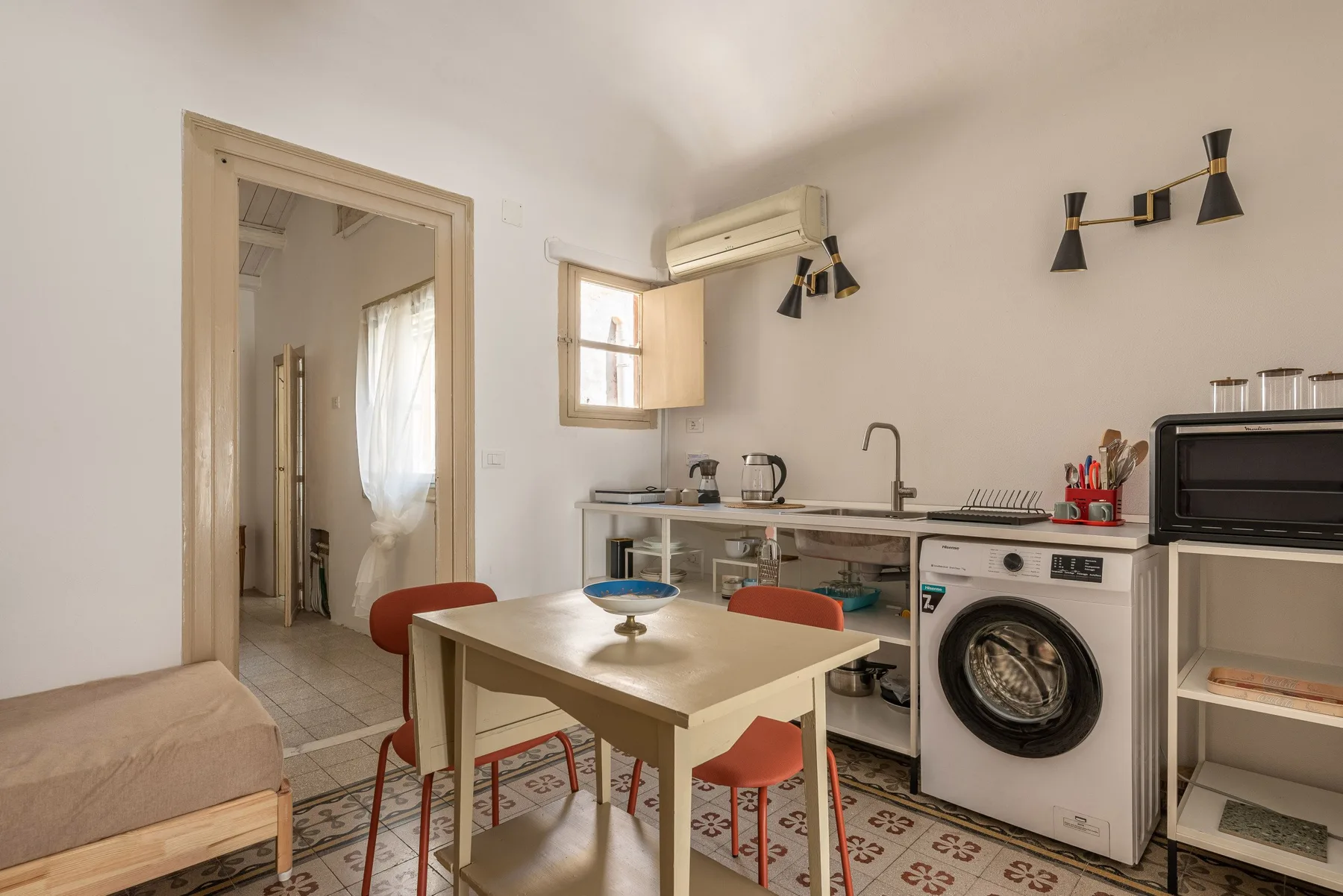 Una mesa de comedor y asientos están junto a una cocina compacta con lavadora.