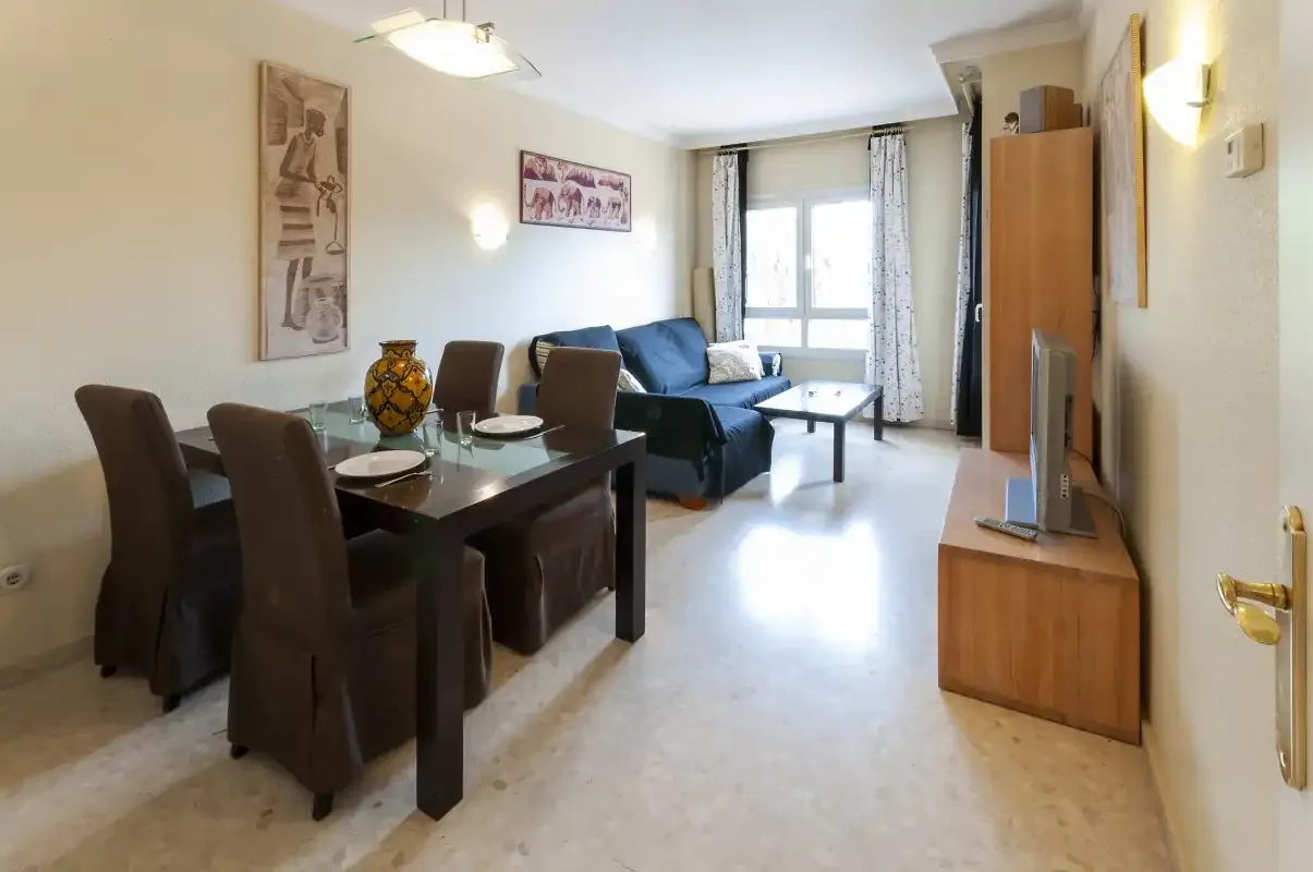 Una zona de estar y comedor con una mesa, asientos y un televisor.