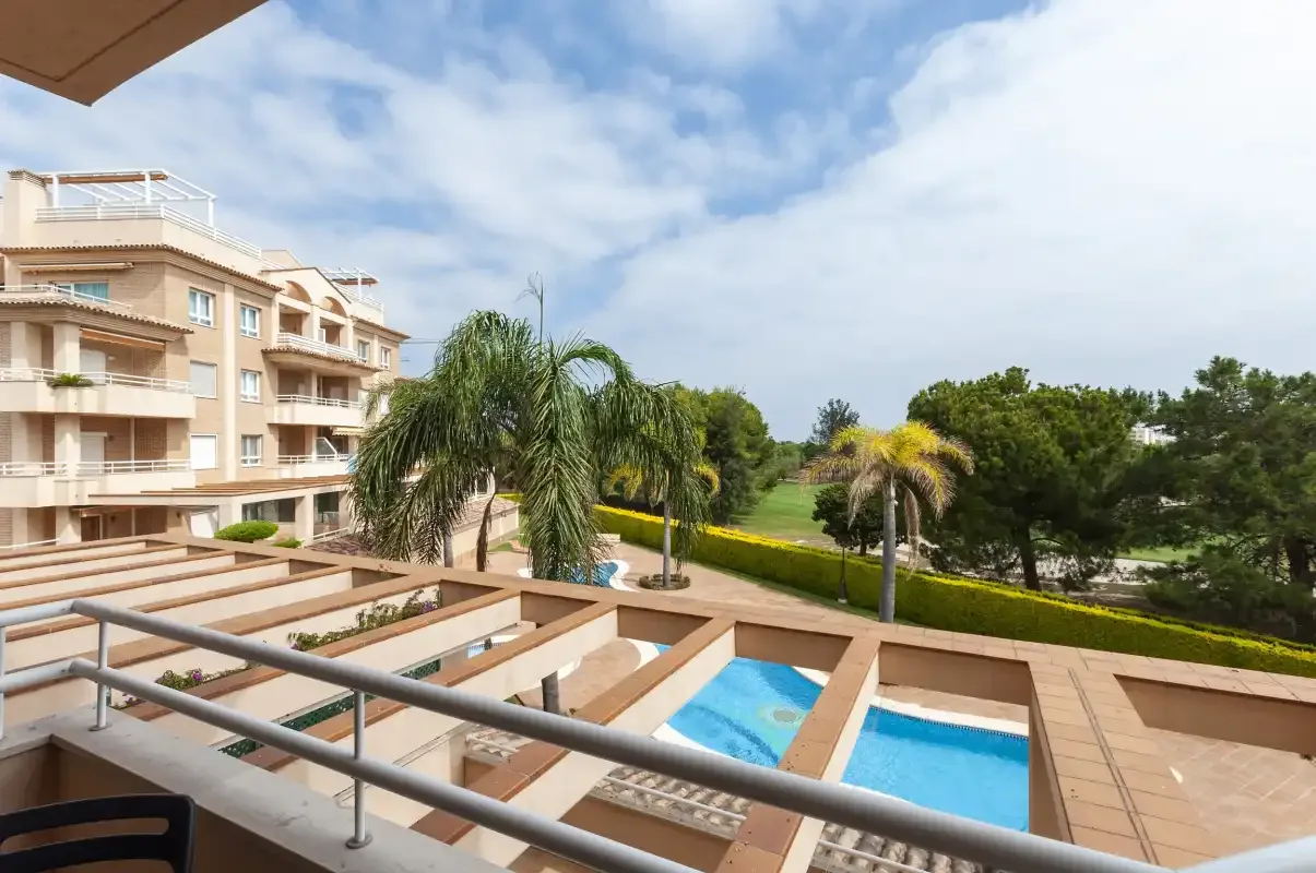 Una zona de piscina al aire libre con palmeras y edificios de apartamentos cercanos.
