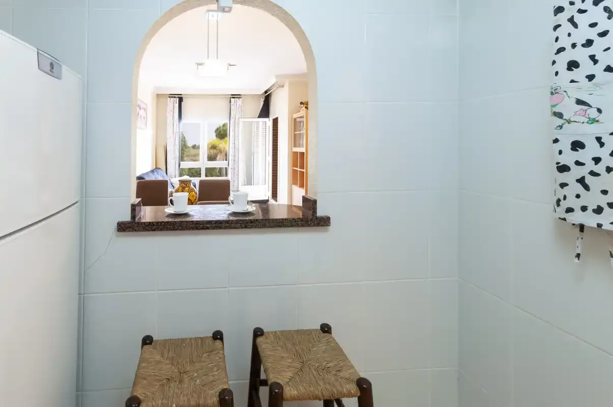 Un baño alicatado con una pequeña ventana que da a un comedor.