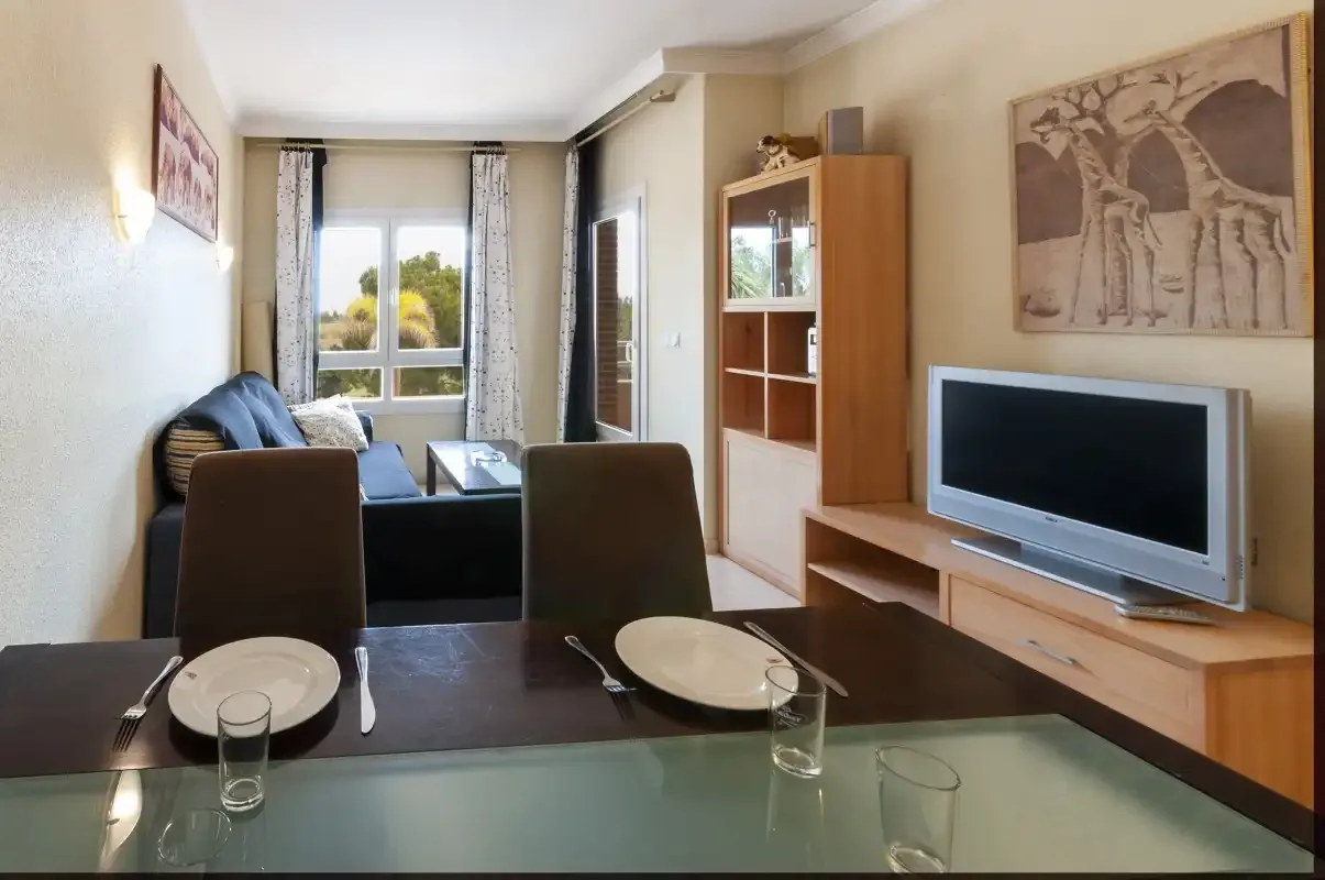 Una sala de estar y comedor con sofá, mesa de comedor y televisor.