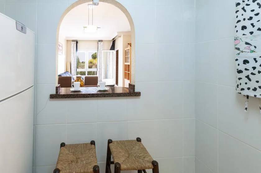 Una zona de cocina con azulejos, un refrigerador y una ventana pasaplatos.