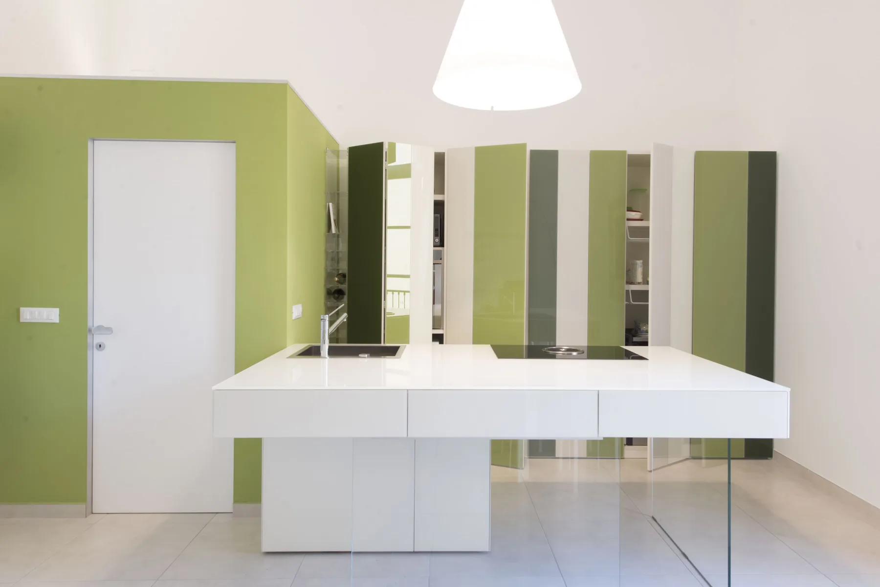 Una cocina moderna con una isla blanca y gabinetes verdes.
