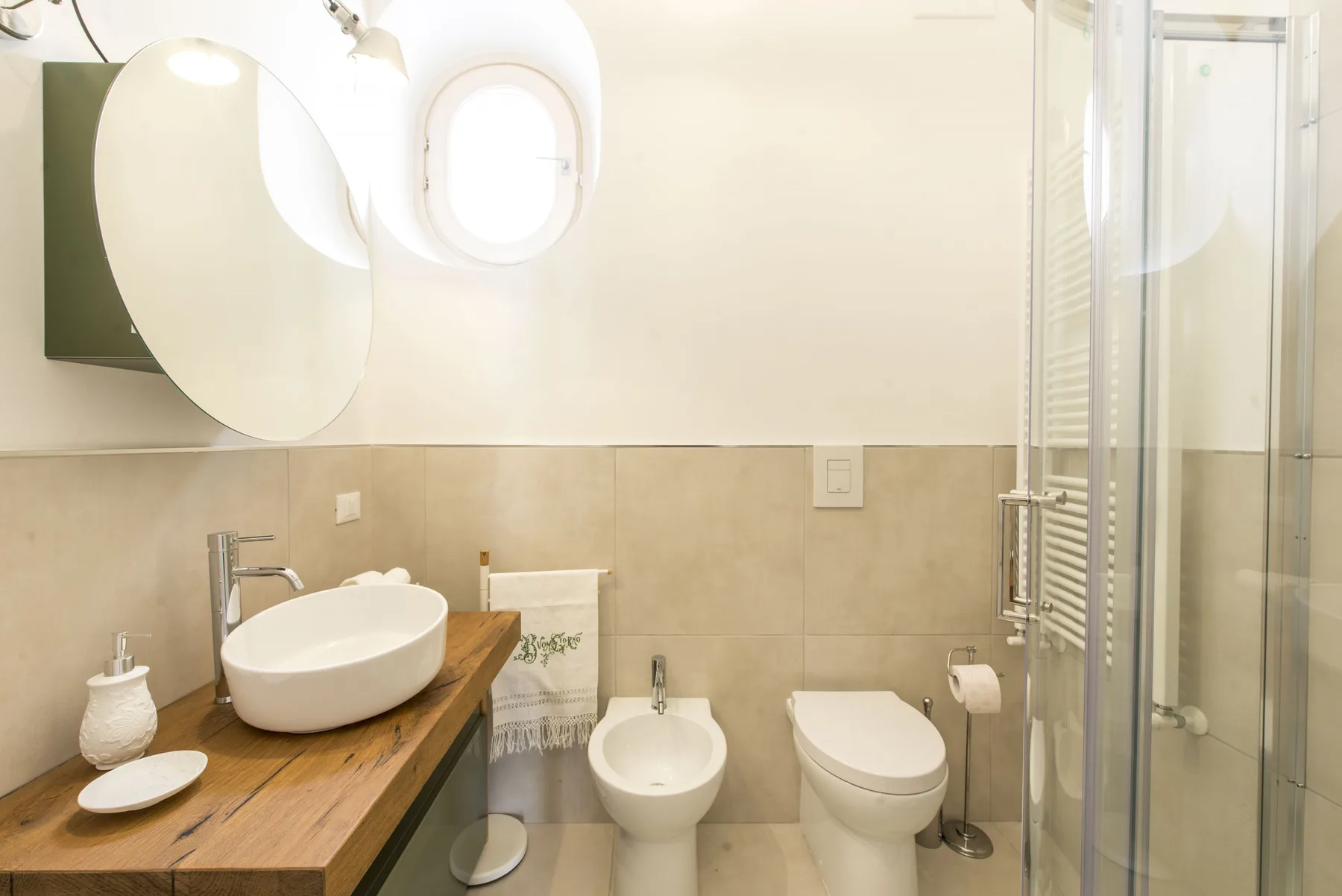 Un baño luminoso con lavabo sobre encimera, inodoro, bidé y ducha de vidrio.
