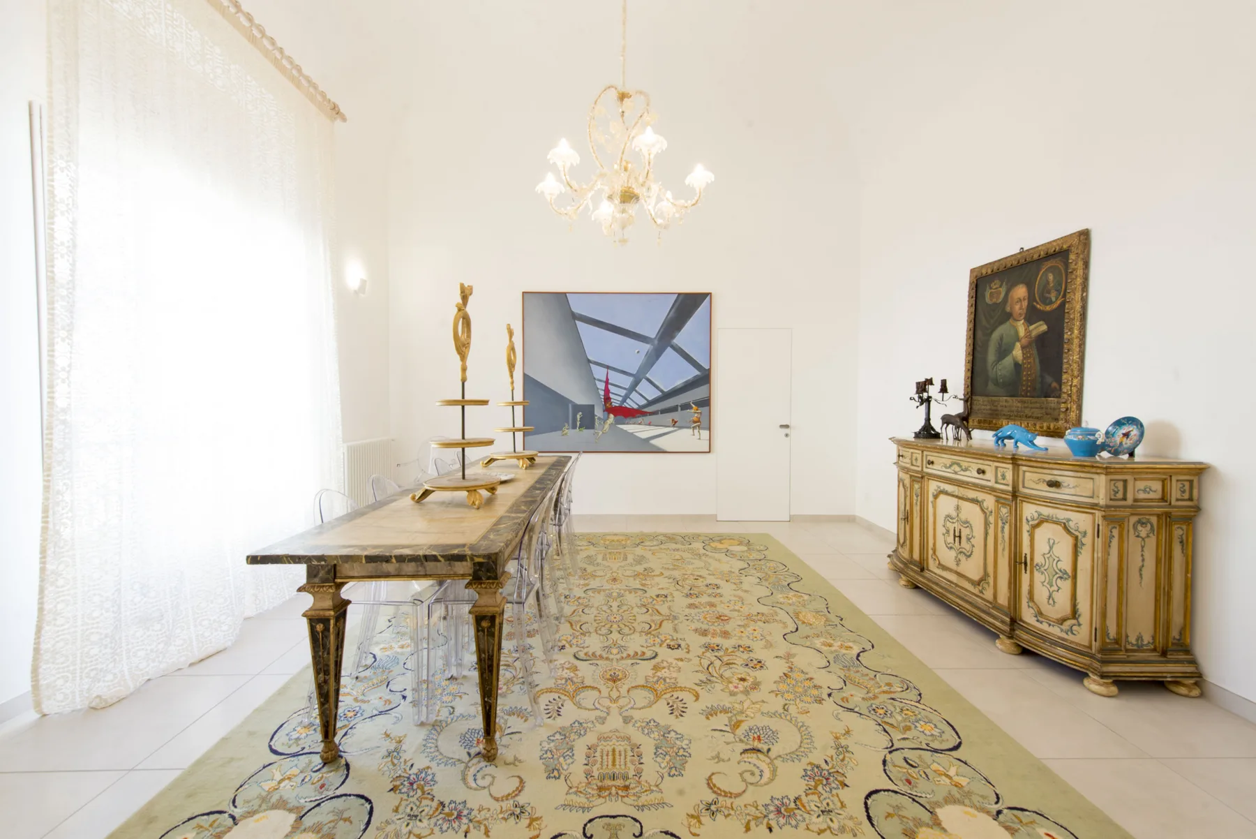Un comedor luminoso con una mesa larga, una alfombra estampada y un aparador ornamentado.