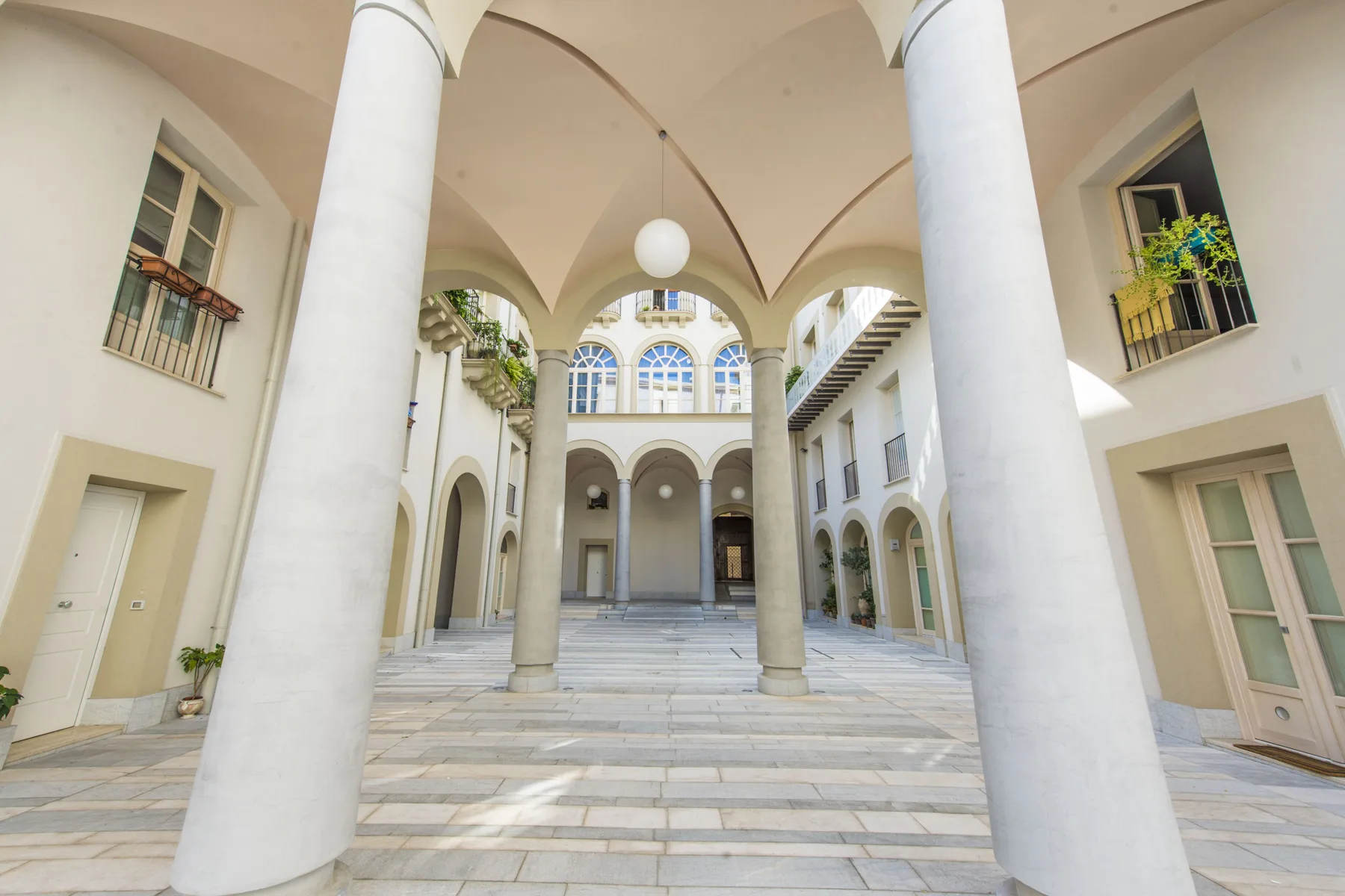Un patio luminoso con pasillos arqueados y columnas altas.