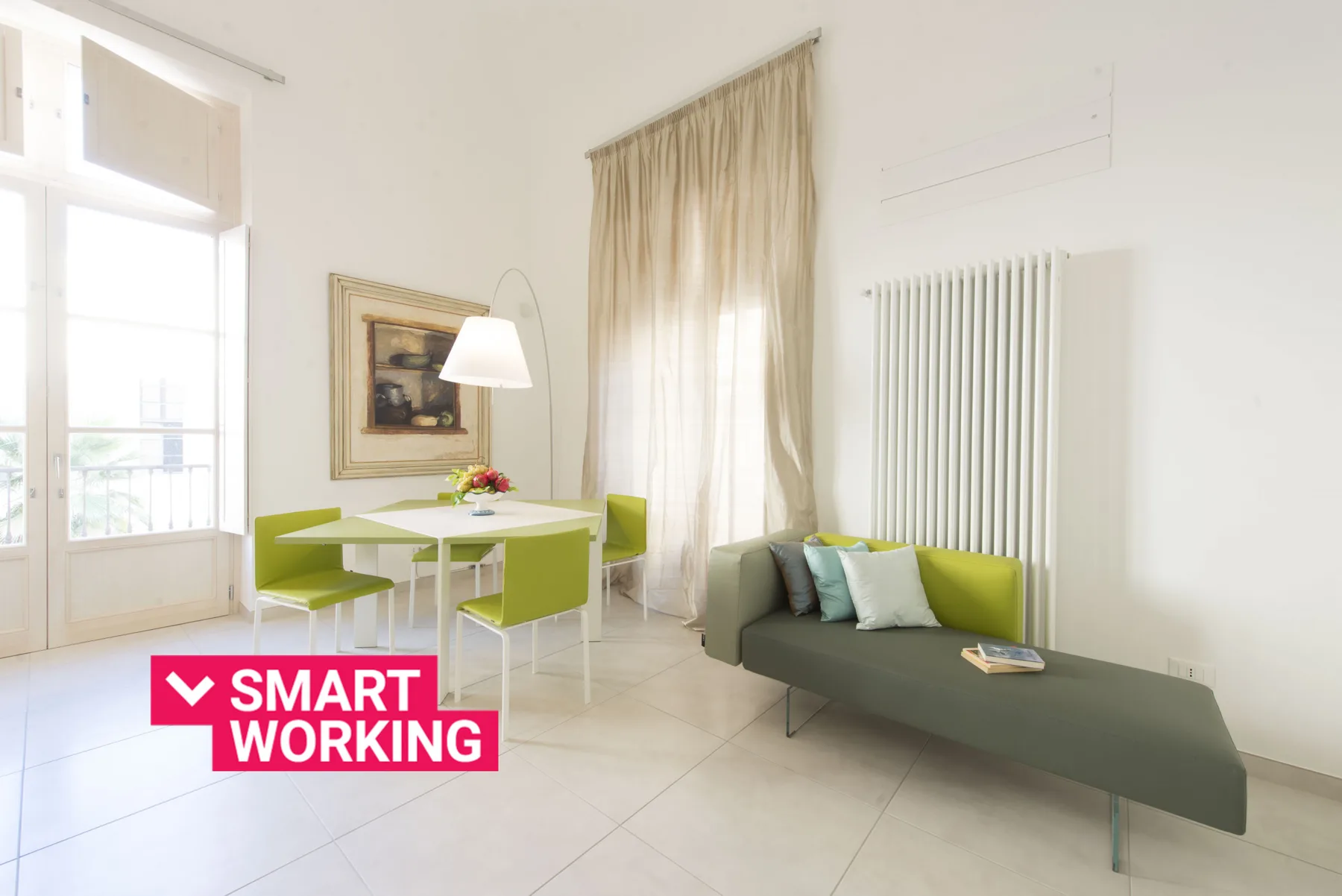 Una luminosa sala de estar con un sofá verde y una pequeña mesa de comedor.