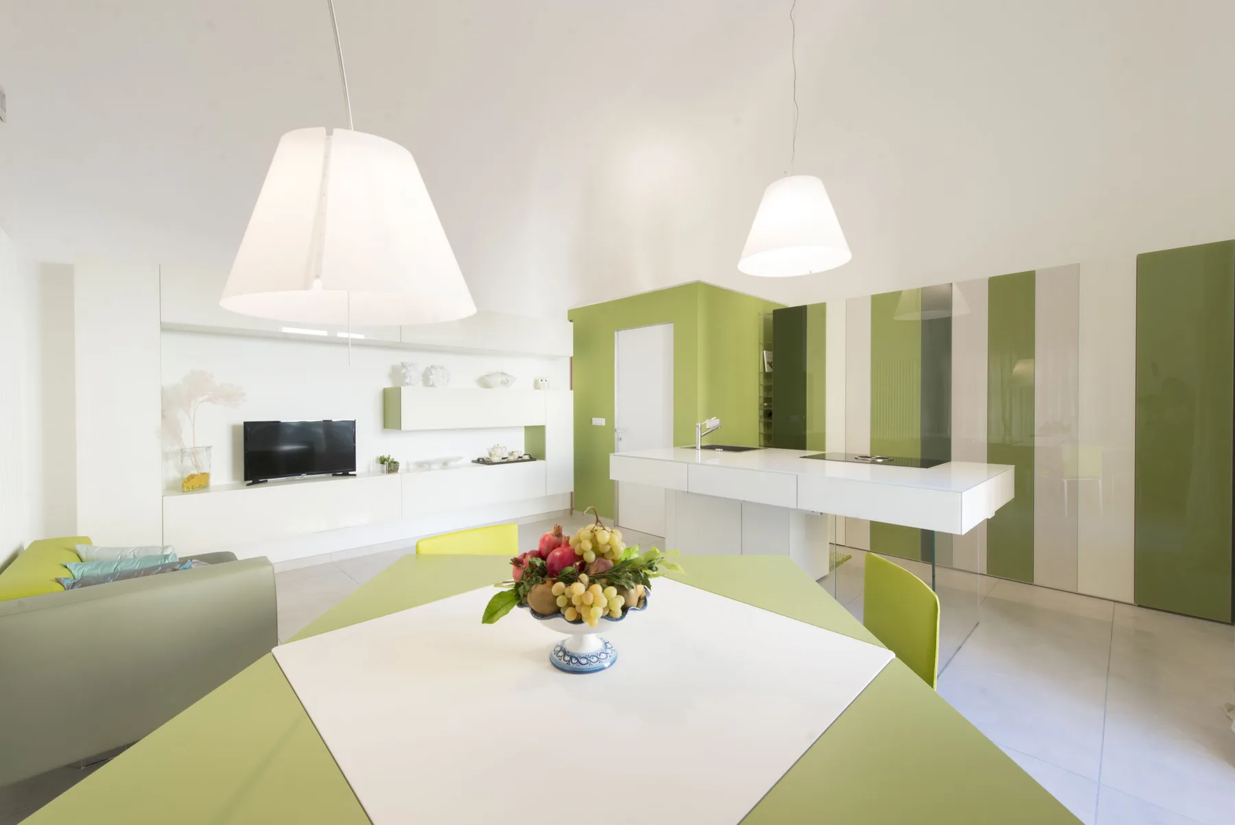 Un comedor moderno y luminoso con una mesa y armarios verdes.