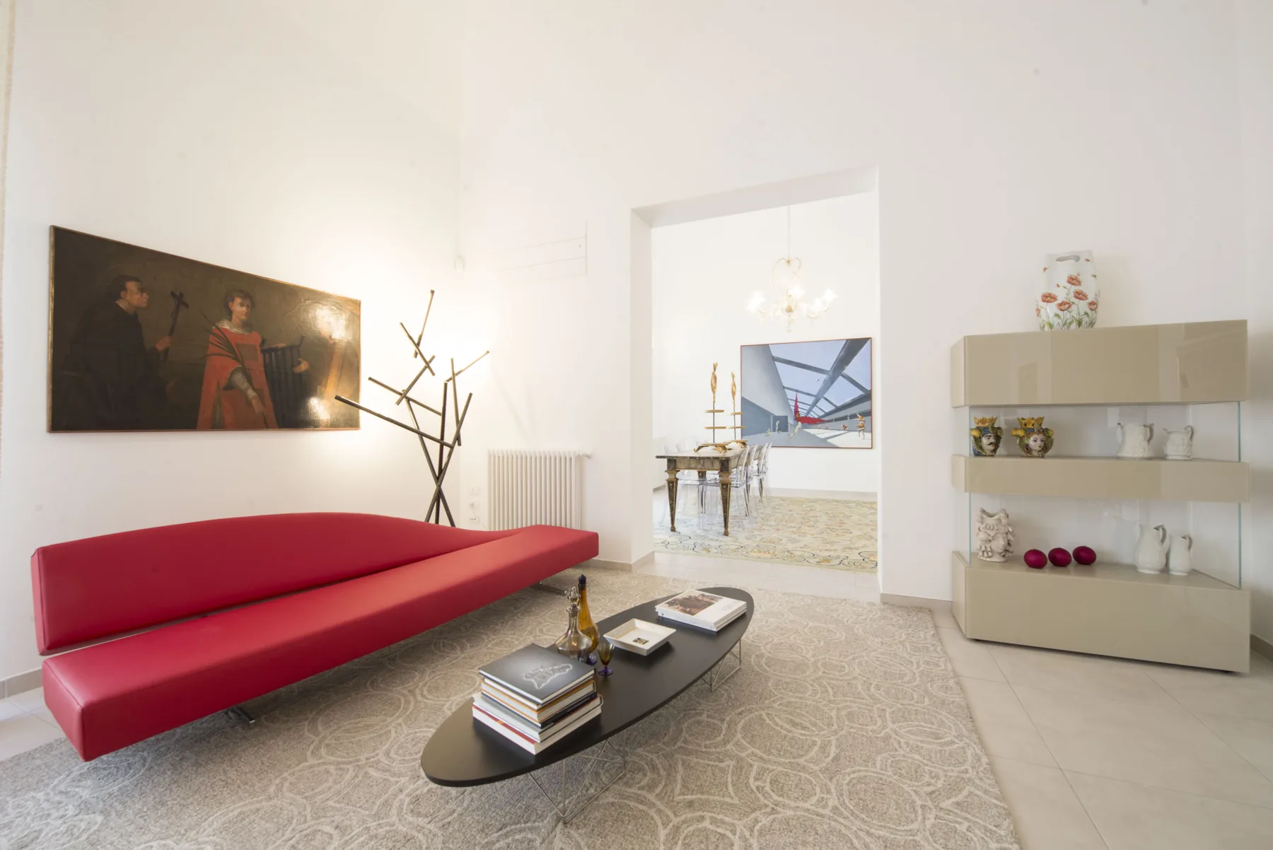 Una sala luminosa con asientos rojos, una mesa de centro oscura y estantes de exhibición.