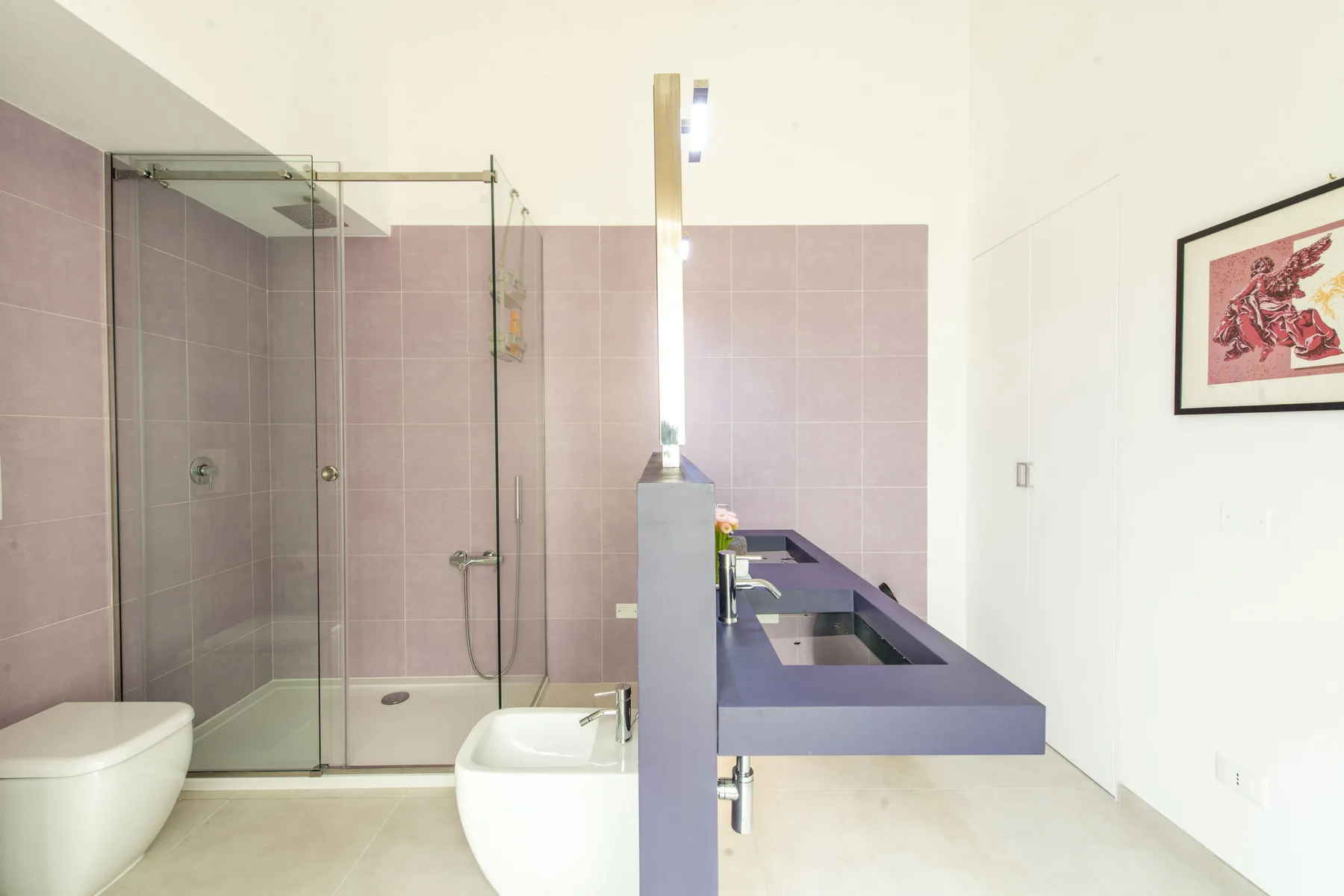 Un baño con ducha de vidrio, bañera y un lavabo alargado.