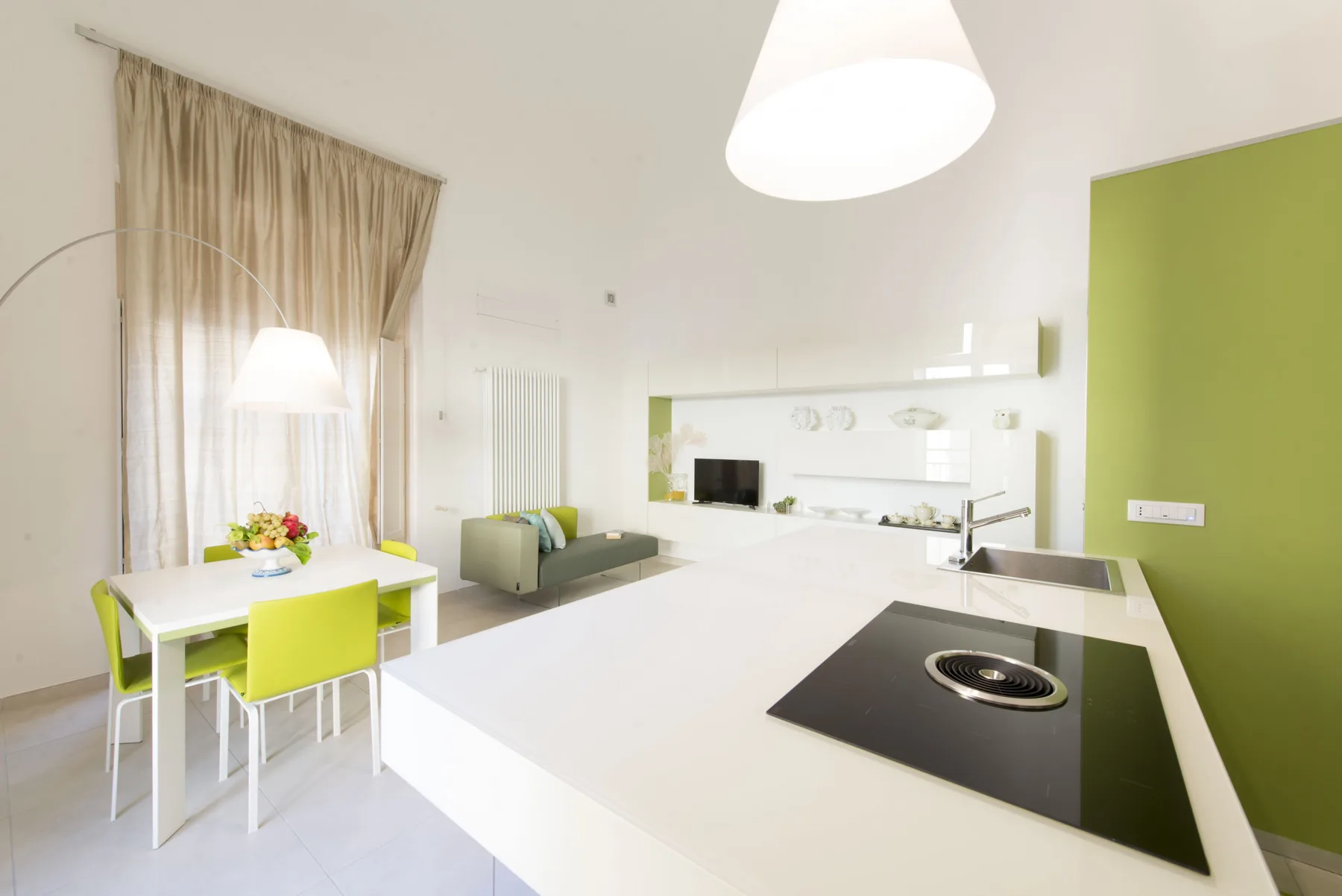 Una cocina y comedor luminosos con una isla blanca y asientos verdes.
